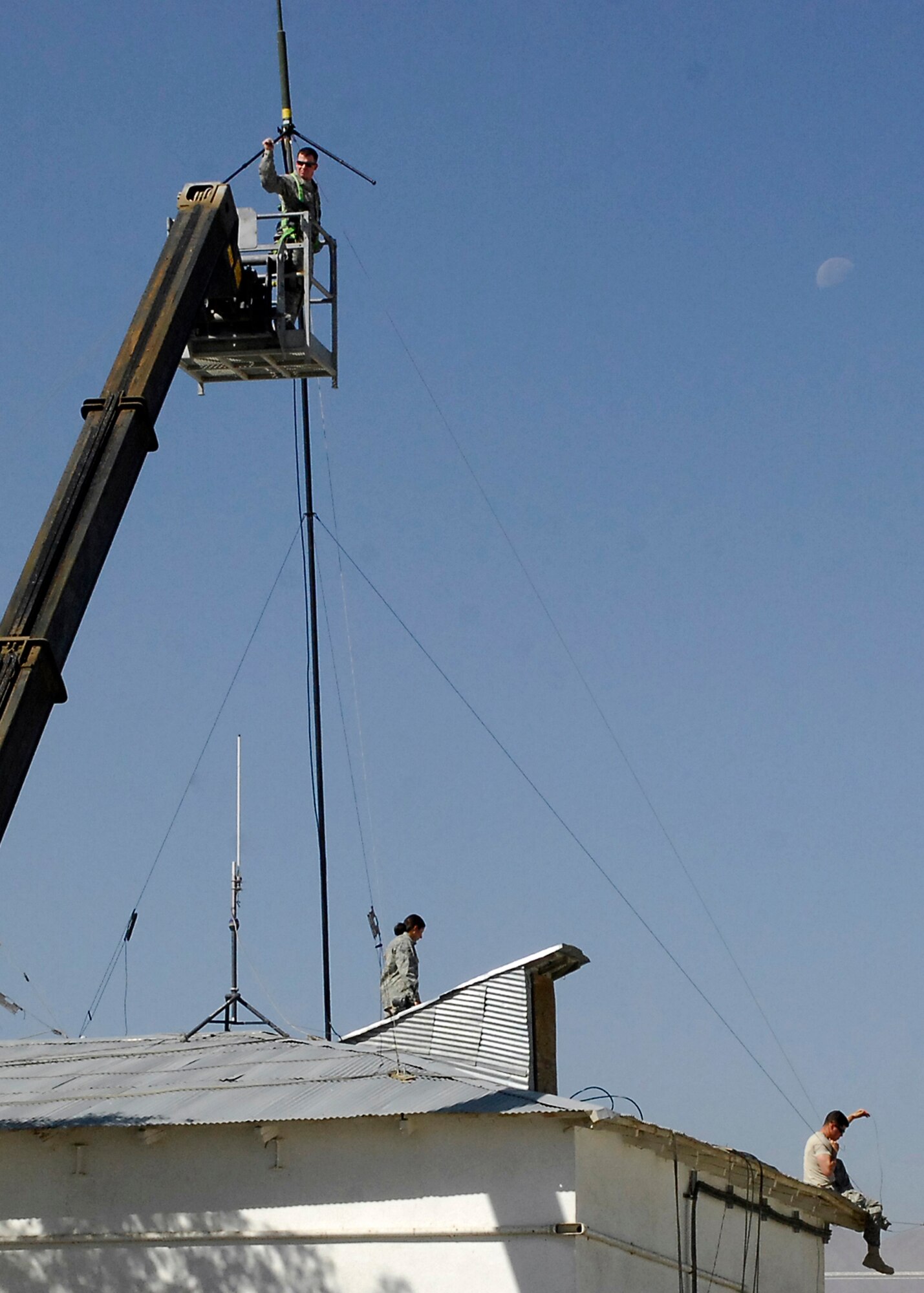BAGRAM AIRFIELD, Afghanistan -- Senior Airman Natalie Richardson (bottom left), Staff Sgt. Jason Richardson (in the bucket), and Airman First Class Kurtis Walter (bottom right) work together to stabilize an antenna here, Oct. 10, 2009.  The three Airmen are all members of the 455th Expeditionary Security Forces Squadron.  Airman Richardson, an Allentown, Pa. native, is deployed from RAF Mildenhall, UK.  Sergeant Richardson, a Cleveland, Ohio native, is deployed from RAF Mildenhall, UK.  Airman Walter is deployed from MacDill Air Force Base, Fla., and hails from Holland, Mich.  (U.S. Air Force photo/Senior Airman Felicia Juenke)