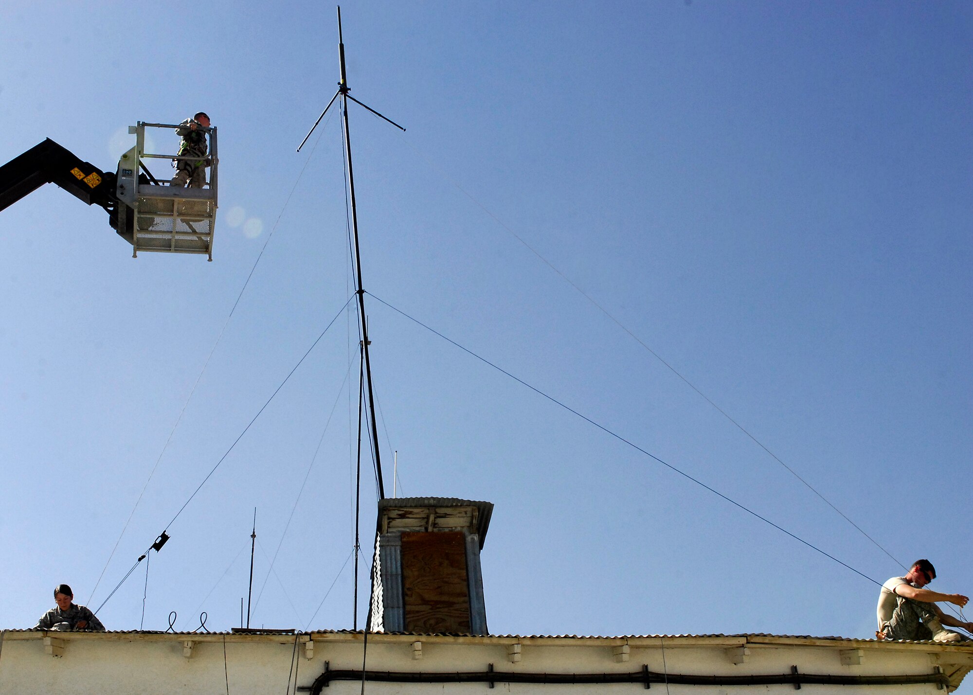 BAGRAM AIRFIELD, Afghanistan -- Senior Airman Natalie Richardson (bottom left), Staff Sgt. Jason Richardson (in the bucket), and Airman First Class Kurtis Walter (bottom right) work together to stabilize an antenna here, Oct. 10, 2009.  The three Airmen are all members of the 455th Expeditionary Security Forces Squadron.  Airman Richardson, an Allentown, Pa. native, is deployed from RAF Mildenhall, UK.  Sergeant Richardson, a Cleveland, Ohio native, is deployed from RAF Mildenhall, UK.  Airman Walter is deployed from MacDill Air Force Base, Fla., and hails from Holland, Mich.  (U.S. Air Force photo/Senior Airman Felicia Juenke)