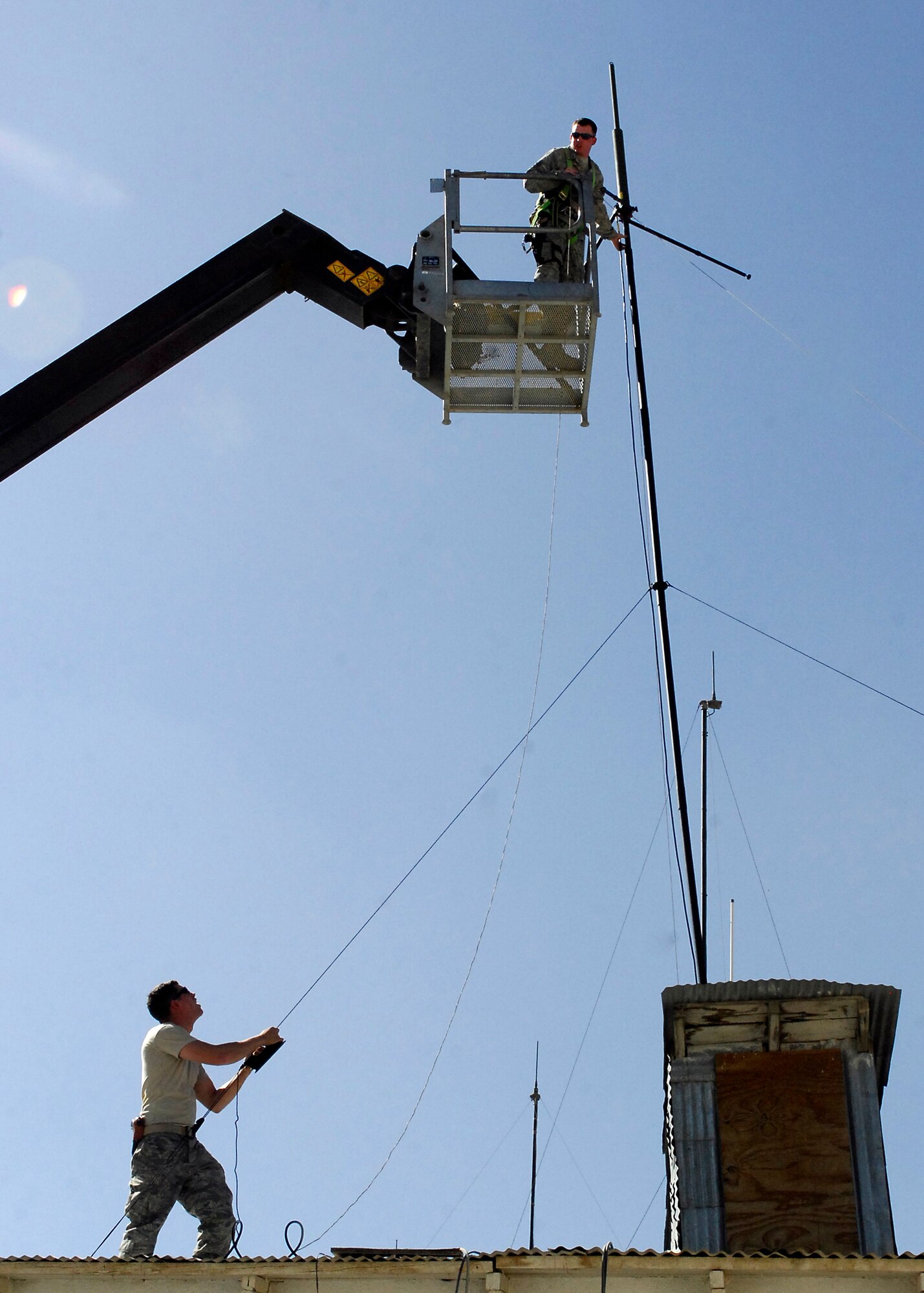 BAGRAM AIRFIELD, Afghanistan -- Airman First Class Kurtis Walter (bottom left), a member of the 455th Expeditionary Security Forces Squadron, secures an antenna with guidance from Staff Sgt. Jason Richardson (in the bucket), also a member of the 455th ESFS, here, Oct. 10, 2009.  The Airmen have to stabilize the antenna so it will function properly and remain safe.  Airman Walter is deployed from MacDill Air Force Base, Fla., and hails from Holland, Mich.  Sergeant Richardson, a Cleveland, Ohio native, is deployed from RAF Mildenhall, UK.  (U.S. Air Force photo/Senior Airman Felicia Juenke)