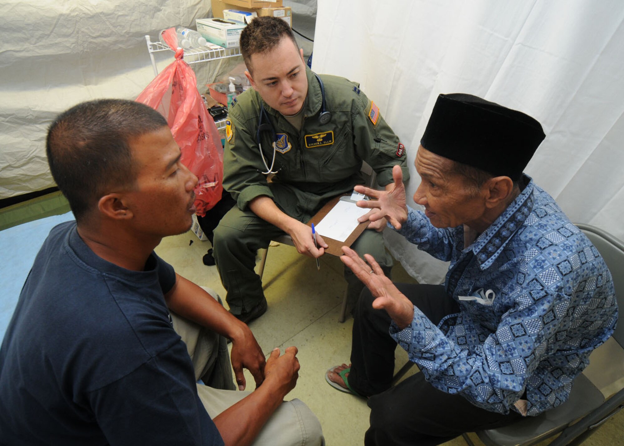 PADANG, Indonesia -- Capt. Steven Ellis collects medical history information from a patient with the help of Khairul, a local interpreter, Oct. 10. Captain Ellis is a flight surgeon from the 36th Medical Group at Andersen Air Force Base, Guam, and is deployed here with a U.S. Air Force humanitarian assistance rapid response team to provide medical assistance to those affected by the recent earthquakes. (U.S. Air Force photo/Staff Sgt. Veronica Pierce)