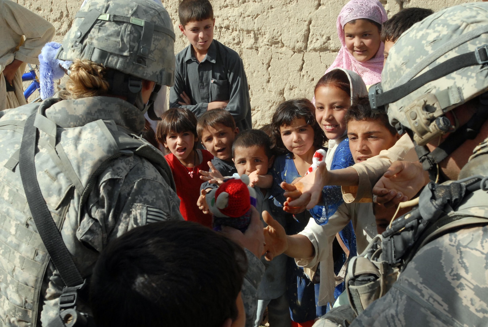 LOGAR PROVINCE, Afghanistan - Tech. Sgts. Michelle Stokes (left) and Brandon Livingstone (right), counter improvised explosive device team, out of Forward Operating Base Shank distribute school supplies, toys and shoes to children in the village of Polerad. (U.S. Army photo/Pfc. Melissa Stewart)