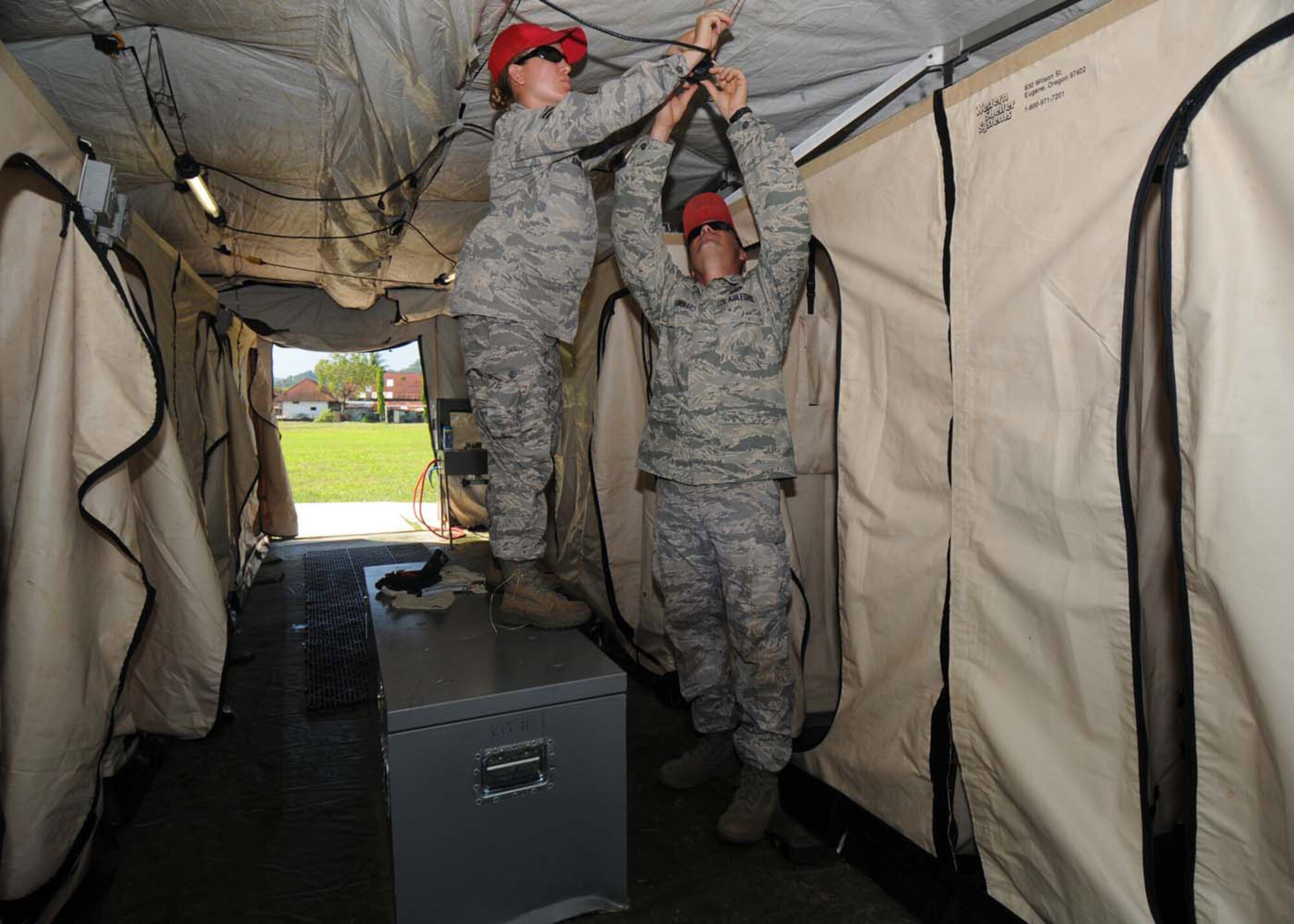 PADANG, Indonesia -- Staff Sgt. Amanda Arndt (left) and Tech. Sgt. Eric Menard install lighting fixtures inside a shower unit to support a U.S. Air Force humanitarian assistance rapid response team Oct. 9. Sergeants Arndt and Menard are from the 554th RED HORSE Squadron at Andersen Air Force Base, Guam, and are deployed here with the HARRT. The squadron provides the Air Force with a highly mobile civil engineering response force to support contingency and special operations worldwide. (U.S. Air Force photo/Staff Sgt. Veronica Pierce)