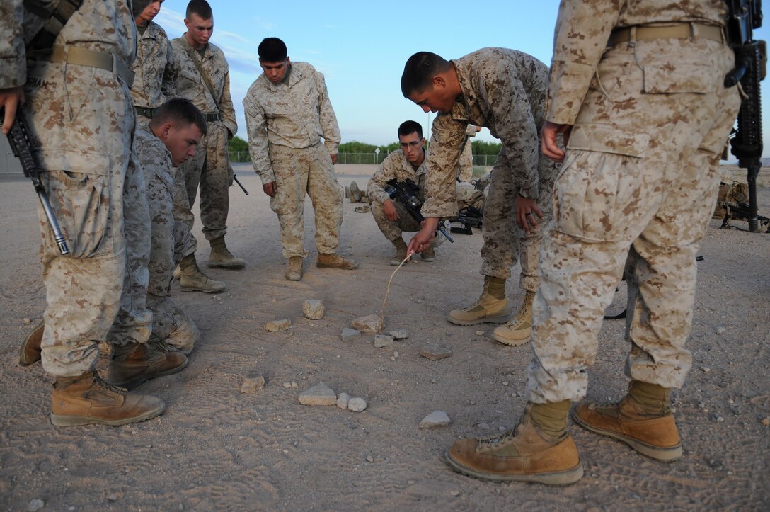 Using a simple model of the town they are assaulting, Marines with E Company, 2nd Battalion, 7th Marine Regiment, review their upcoming mission near the flight line at the Marine Corps Air Station in Yuma, Ariz., before a helicopter raid training exercise Oct. 10, 2009. Loading on to MV-22 Osprey aircraft in Yuma, the company's 1st Platoon flew to an urban training range in Twentynine Palms, Calif., in order to capture an insurgent leader, simulating a mission they could be called to perform during their next deployment. The battalion, based in Twentynine Palms, is scheduled to deploy with the 31st Marine Expeditionary Unit in early 2010, with E Company assigned to specialize in helicopter insertions and raids.