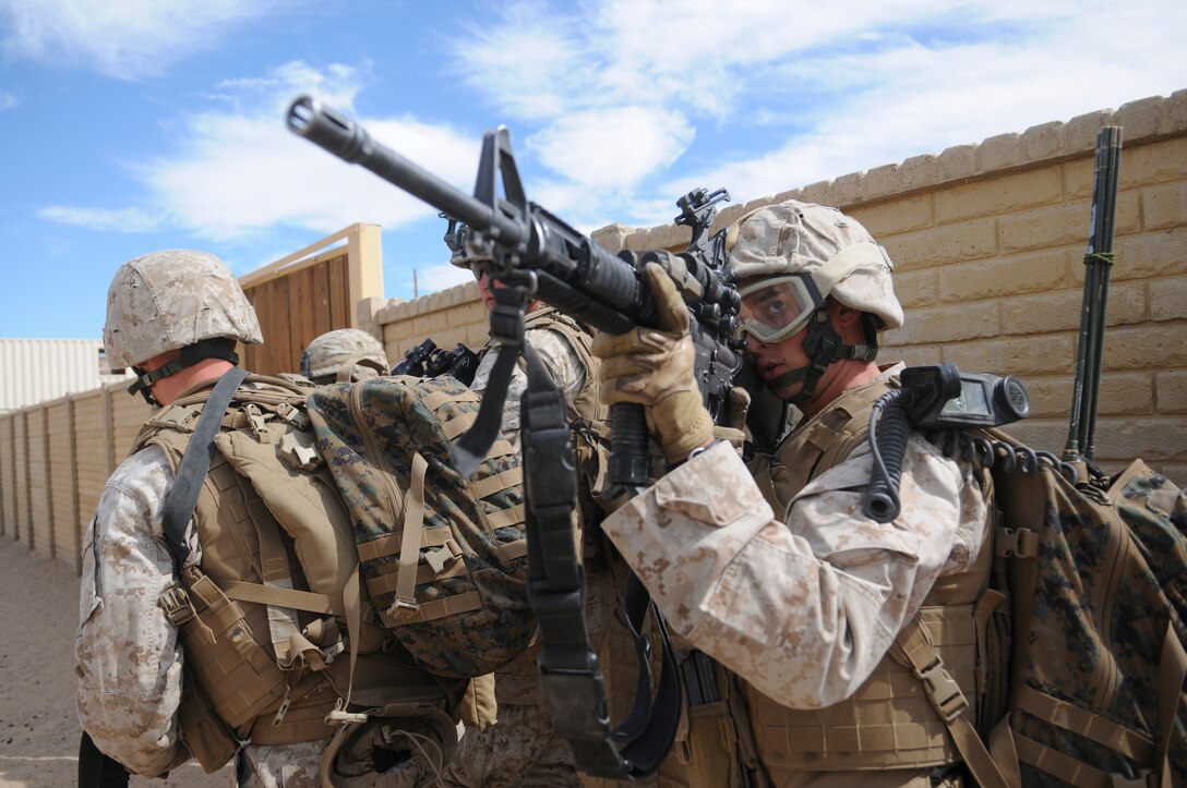 Lance Cpl. Matt P. Owens, rifleman and radio operator, watches for snipers in an urban training range in Twentynine Palms, Calif., on Oct. 10, 2009. The company's 1st Platoon flew from the Marine Corps Air Station in Yuma, Ariz, to Twentynine Palms, Calif., in order to raid a town and capture an insurgent leader, simulating a mission they could be called to perform during their next deployment. The battalion, based in Twentynine Palms, is scheduled to deploy with the 31st Marine Expeditionary Unit in early 2010, with E Company assigned to specialize in helicopter insertions and raids. Owens, 19, is a native of Bismark, Ill.