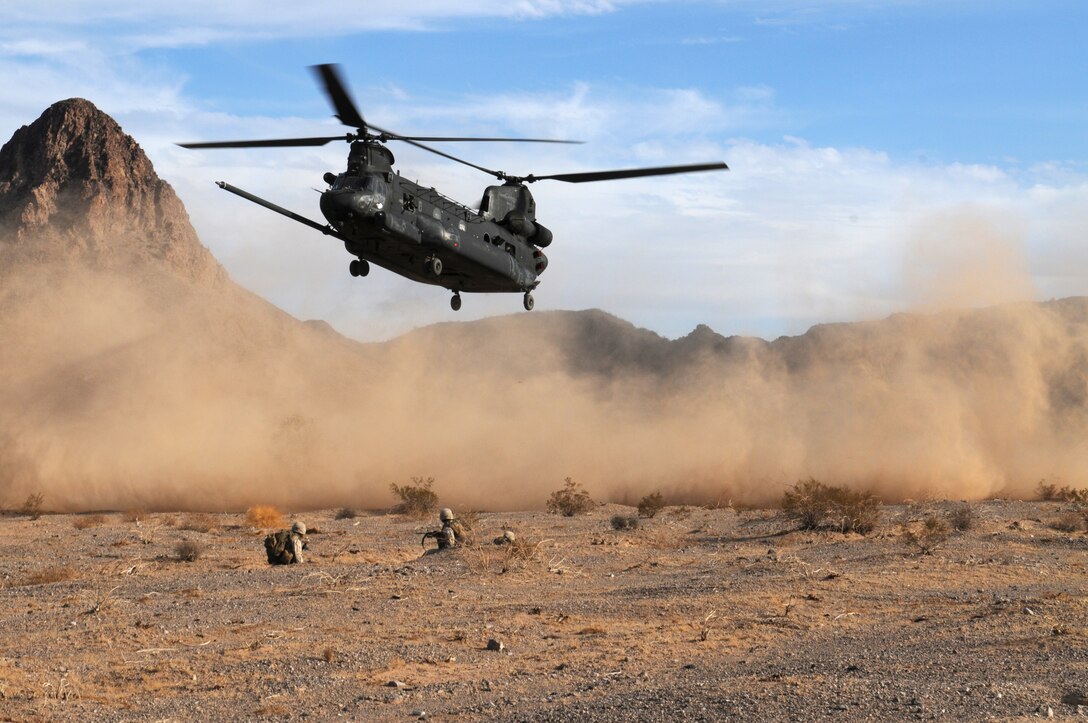 Marines with E Company, 2nd Battalion, 7th Marine Regiment, are covered in desert dust as they wait for an Army CH-47 Chinook to land on the Barry M. Goldwater Range east of the Marine Corps Air Station in Yuma, Ariz., Oct. 10, 2009. The Marines were dropped off by the Chinook and CH-46E Sea Knights for an assault training exercise. Army officers, using their aircraft, also participate in the Weapons and Tactics Instructor course taught by Yuma-based Marine Aviation Weapons and Tactics Squadron 1. The 2/7 Marines are based at Marine Corps Air Ground Combat Center in Twentynine Palms, Calif., and are here training for an upcoming deployment with the 31st Marine Expeditionary Unit.