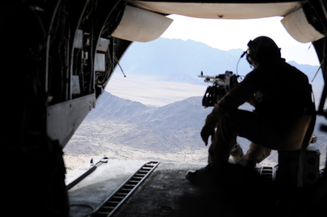 While ready to operate the mounted M-240 machine gun, Sgt. Jeffrey McCarstle, CH-46E Sea Knight crew chief, looks out of the back of the aircraft Oct. 10, 2009, as it transports Marines with 2nd Battalion, 7th Marine Regiment, approximately 70 miles east of the Marine Corps Air Station in Yuma, Ariz., for an assault. Along the way, McCarstle and two other crew members operated the three machine guns on the helicopter, firing at makeshift enemy targets resembling automobiles. The battalion is based at Twentynine Palms, Calif., and scheduled to deploy with the 31st Marine Expeditionary Unit in early 2010, which is based in Okinawa, Japan.