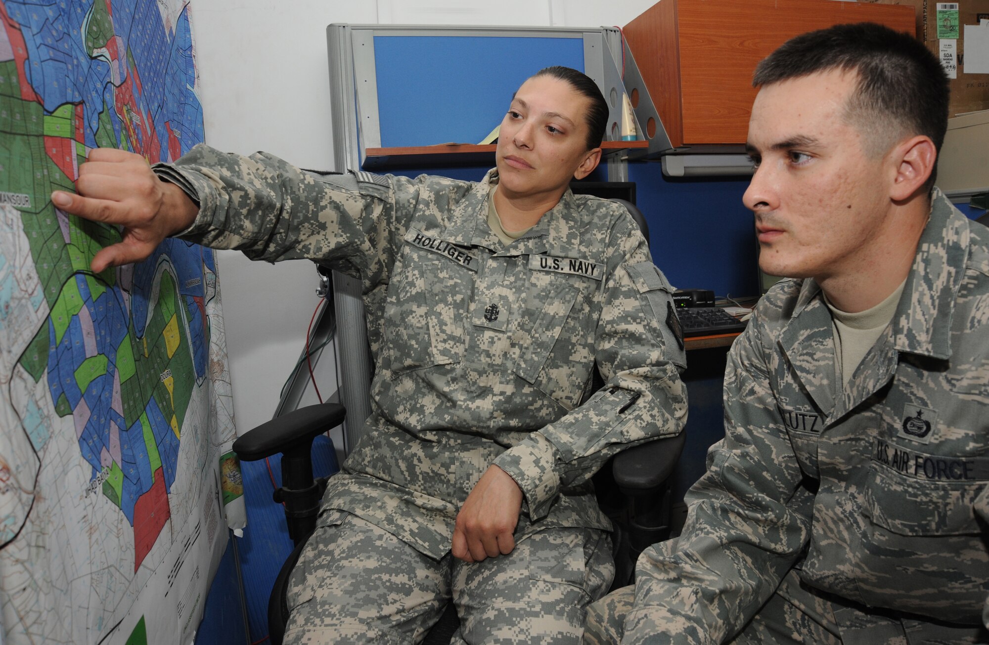 CAMP VICTORY, Iraq -- Navy Chief Petty Officer Jill Holliger, Combined Joint Task Force Troy Functional Analysis Cell assistant noncommissioned officer in charge, and Air Force MSgt Michael Clutz, CJTF Troy FAC NCOIC, look at sectarian neighborhoods here on a map of Baghdad. FAC members analyze improvised explosive devices emplacement activity. Chief Holliger is deployed from Command Patrol and Reconnaissance Wing 10, Whidbey Island, Wash., and is a native of Diller, Neb. Sergeant Clutz is deployed from Bolling Air Force Base, Washington, D.C., and hails from Corpus Christi, Texas. (U.S. Air Force photo/Tech. Sgt. Johnny L. Saldivar)