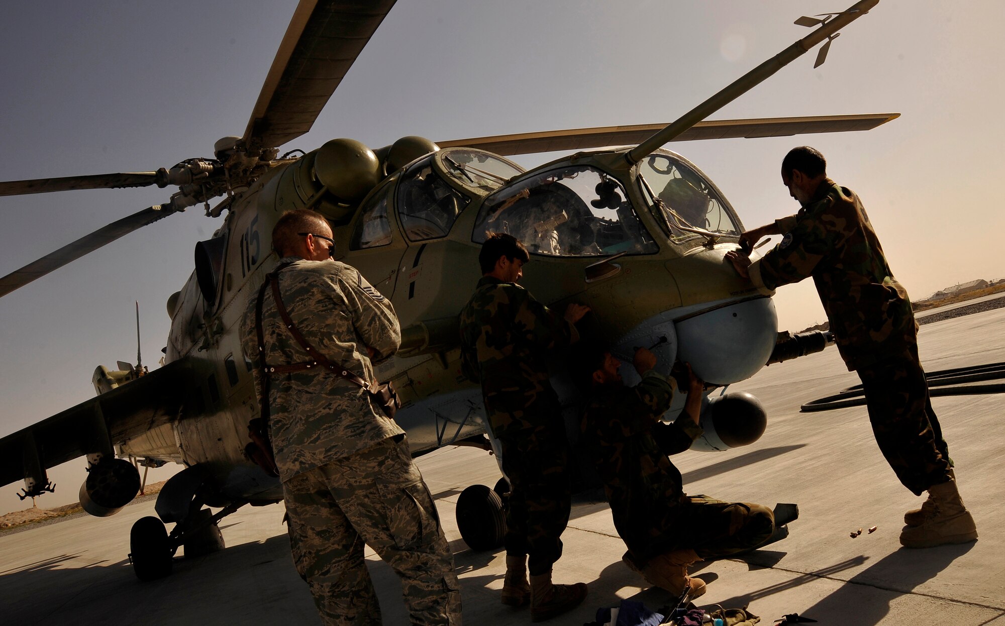 Airmen from the Afghan National Army Air Corps prepare an Mi-35 Hind helicopter for a training mission Oct. 4, 2009 at Kandahar Air Field while a U.S. Air Force Airman from the 438th Air Expeditionary Training Group observes in a support role. (U.S. Air Force photo/Staff Sgt. Angelita Lawrence)