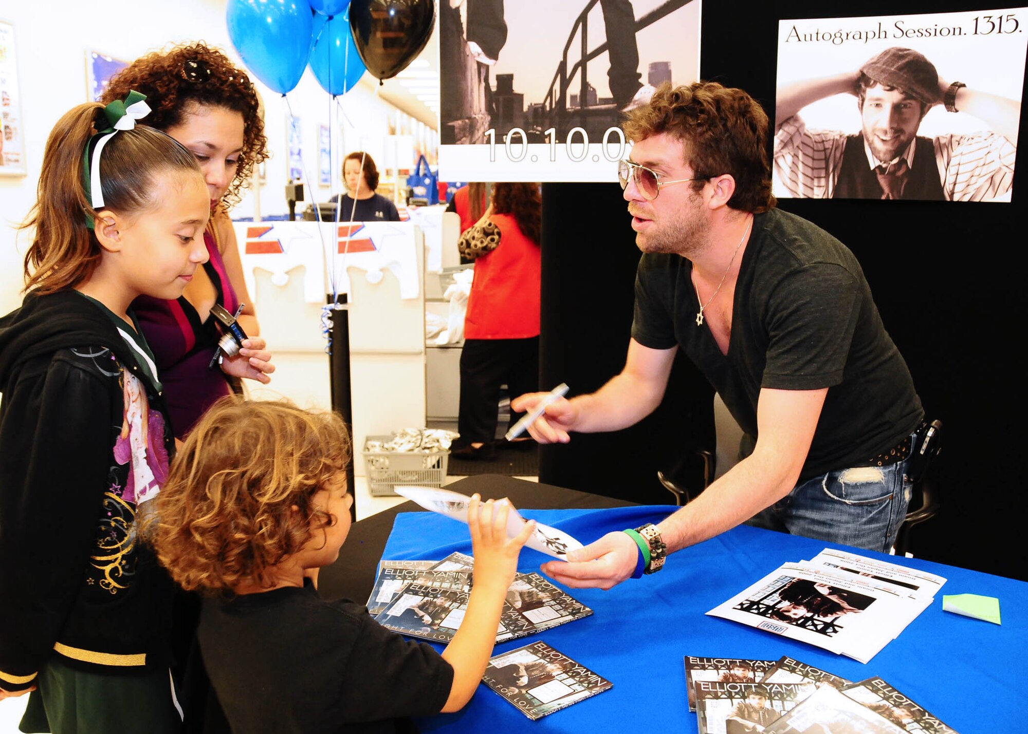 ANDERSEN AIR FORCE BASE, Guam - Rythym and blues sensation and former American Idol contestant Elliott Yamin signs autographs for Paul Rodgers, sister Sumaya and mother Saidee' at the base exchange  Oct. 10. Elliott Yamin performed various songs live including his hit songle "Wait for You" at a concert attended by more than 250 Airmen, Sailors and their families at Bamboo Willie's. (U.S. Air Force photo by Senior Airman Nichelle Anderson)