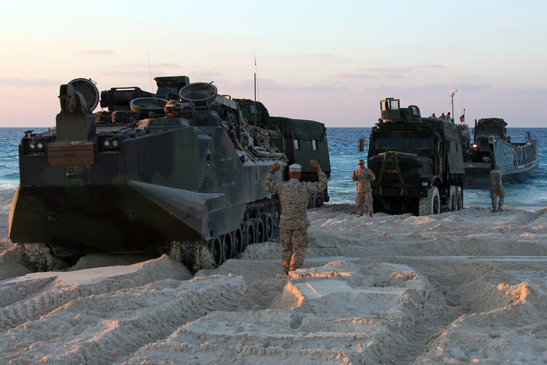 Sgt Paul H. Cunningham, foreground, an Amphibious Assault Vehicle Mechanic and native of Gettysburg, S.D., and Sgt. Derek R. Sherman, a welder and native of Jacksonville, Fla., both with India Company, Battalion Landing Team, 3rd Battalion, 2nd Marine Regiment, 22nd Marine Expeditionary Unit, guide an AAV R7A1 on the beach during Exercise Bright Star 2009 in Egypt Oct. 11, 2009. The multinational exercise is designed to improve readiness, interoperability, and strengthen the military and professional relationships among U.S., Egyptian and participating forces. Bright Star is conducted by U.S. Central Command and held every two years. Elements of the 22nd MEU are currently are participating in the multi-national exercise while serving as the theater reserve force for U.S. Central Command.::r::::n::(Official Marine Corps photo by Cpl. Theodore W. Ritchie)::r::::n::