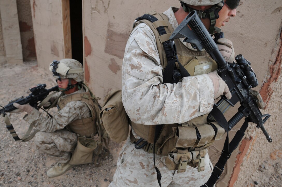 Sgt. Patrick R. Stephens, right, squad leader with E Company, 2nd Battalion, 7th Marine Regiment, calls in his position while Lance Cpl. Matthew J. Huebsch watches his back in an urban training range at the U.S. Army Yuma Proving Ground in Arizona during a helicopter raid exercise Oct. 12, 2009. Sixteen Marines landed on the outskirts of the range in four UH-1 helicopters and stormed the buildings from all sides searching for two insurgent leaders, simulating a mission they could be called to perform during their next deployment. The battalion, based in Twentynine Palms, Calif., is scheduled to deploy with the 31st Marine Expeditionary Unit in early 2010, with E Company assigned to specialize in helicopter insertions and raids. Stephens, 25, is a native of Austin, Texas, and Huebsch, 23, is a native of St. Ansgar, Iowa.