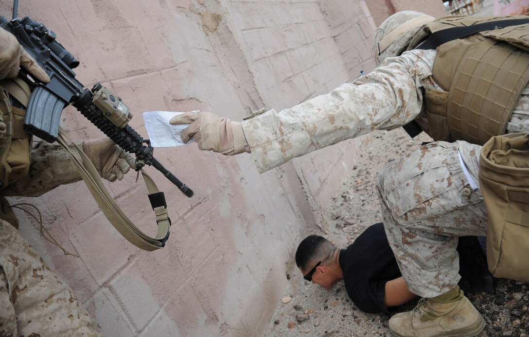 Sgt. Patrick R. Stephens, right, squad leader with E Company, 2nd Battalion, 7th Marine Regiment, hands a map of the village he seized from a mock insurgent to Lance Cpl. Matthew J. Huebsch in an urban training range at the U.S. Army Yuma Proving Ground in Arizona during a helicopter raid exercise Oct. 12, 2009. Sixteen Marines landed on the outskirts of the range in four UH-1 helicopters and stormed the buildings from all sides searching for two insurgent leaders, simulating a mission they could be called to perform during their next deployment. The battalion, based in Twentynine Palms, Calif., is scheduled to deploy with the 31st Marine Expeditionary Unit in early 2010, with E Company assigned to specialize in helicopter insertions and raids. Stephens, 25, is a native of Austin, Texas, and Huebsch, 23, is a native of St. Ansgar, Iowa.