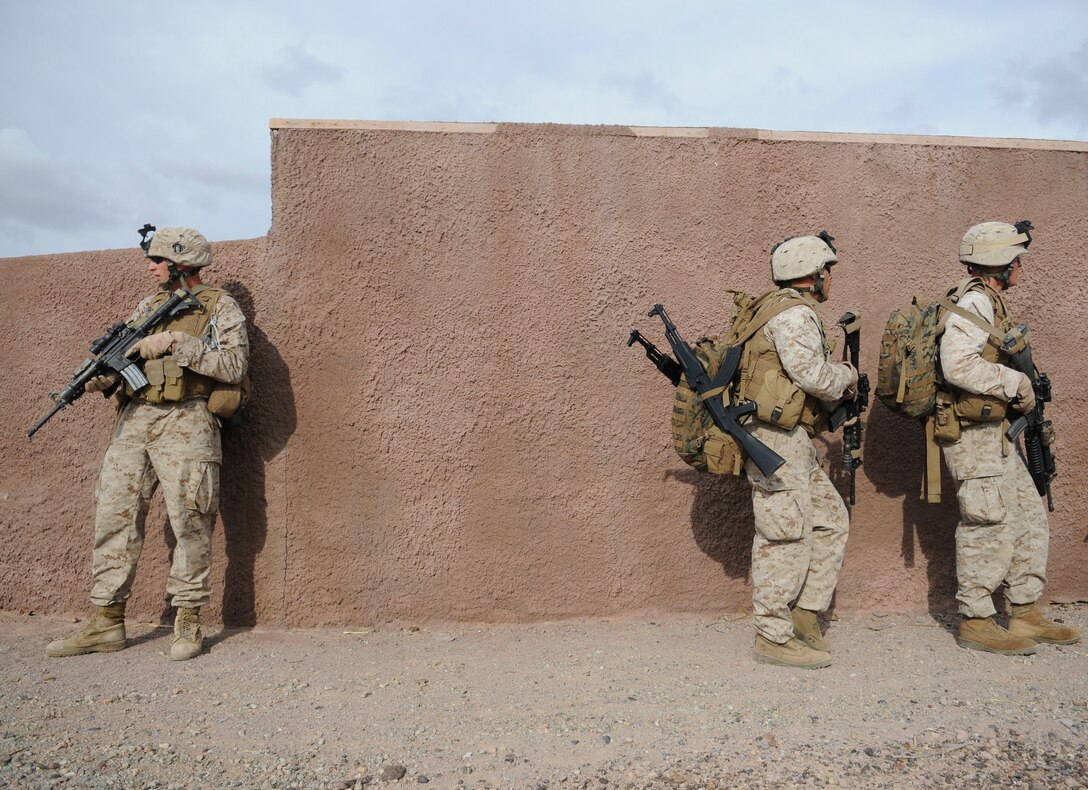 Lance Cpl. Mark W. Briggs, left, Lance Cpl. Tyson G. Bainum and Lance Cpl. Tyler Steffins with E Company, 2nd Battalion, 7th Marine Regiment, halt behind a wall moments before rushing to a landing site where they will be extracted in UH-1 helicopters from an urban training range at the U.S. Army Yuma Proving Ground in Arizona during a helicopter raid exercise Oct. 12, 2009. Sixteen Marines landed on the outskirts of the range in four UH-1 helicopters and stormed the buildings from all sides searching for two insurgent leaders, simulating a mission they could be called to perform during their next deployment. The battalion, based in Twentynine Palms, Calif., is scheduled to deploy with the 31st Marine Expeditionary Unit in early 2010, with E Company assigned to specialize in helicopter insertions and raids. Briggs, 25, is Salt Lake City-native, Bainum, 20, is a native of Canyon, Texas, and Steffins, 21, is from Marysville, Wash.