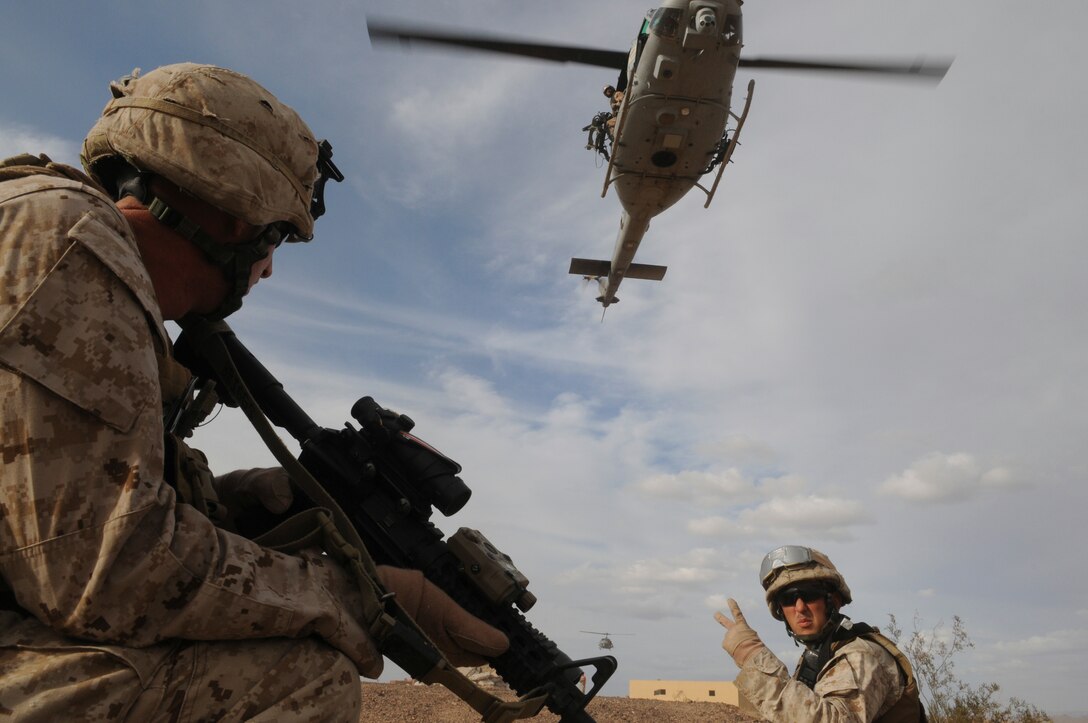 Sgt. Patrick R. Stephens, right, squad leader with E Company, 2nd Battalion, 7th Marine Regiment, signals Lance Cpl. Mark W. Briggs before extraction by in UH-1 helicopters from an urban training range at the U.S. Army Yuma Proving Ground in Arizona during a helicopter raid exercise Oct. 12, 2009. Sixteen Marines landed on the outskirts of the range in four UH-1 helicopters and stormed the buildings from all sides searching for two insurgent leaders, simulating a mission they could be called to perform during their next deployment. The battalion, based in Twentynine Palms, Calif., is scheduled to deploy with the 31st Marine Expeditionary Unit in early 2010, with E Company assigned to specialize in helicopter insertions and raids. Stephens, 25, is a native of Austin, Texas, and Briggs, 25, is a Salt Lake City native.