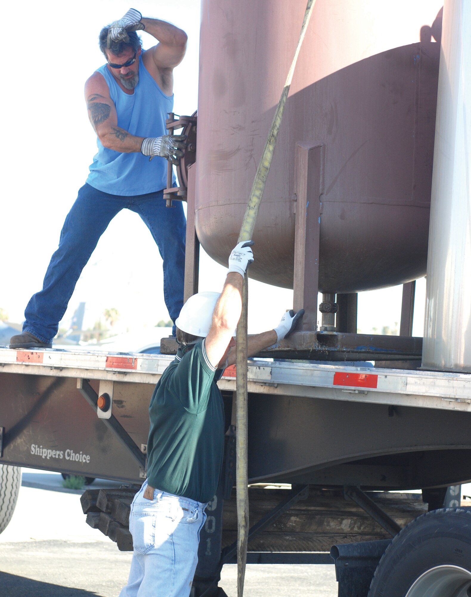 Two base contractors guide a crane-lifted tank onto a truck bed Sept. 22. The tank was part of the ground water and soil vapor extraction system that was installed in 1997. After cleaning an equivalent of 58,000 gallons of jet fuel, the system is no longer needed. (U.S. Air Force photo by Staff Sgt. Megan Crusher)
