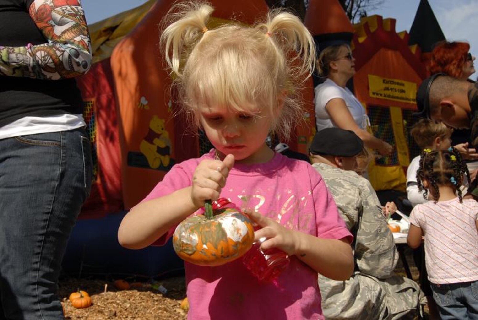 Molly Mae Theodoroff, daughter of Master Sgt. Timothy Theodoroff, a satellite technician with the 129th Communications Flight, takes a time out from the bounce houses to admire her arts and crafts pumpkin at the 129th Rescue Wing’s annual Family Day Picnic hosted Oct. 3 at Moffett Federal Airfield, Calif. (Air National Guard photo by Tech. Sgt. Ray Aquino)