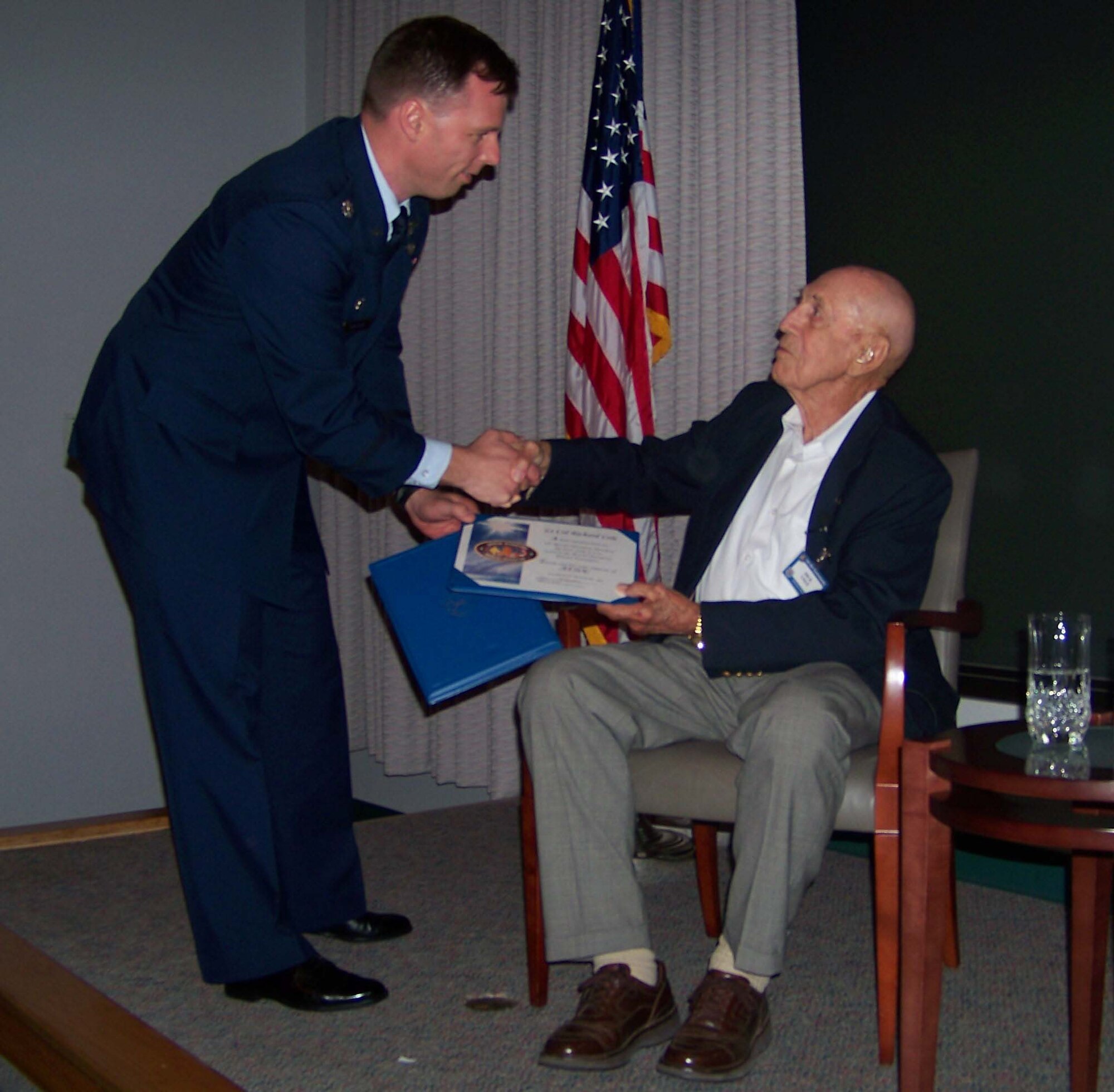 Lt. Col. Dagvin Anderson, left, presents retired Col. Richard Cole with a certificate of appreciation and a $500 donation made out in Colonel Cole's name to the Special Operations Warrior Foundation during the Air Commando Heritage Symposium at the Air Force Special Operations Training Center auditorium at Hurlburt Field Oct. 9. (U.S. Air Force photo by Airman 1st Class Joe McFadden.)