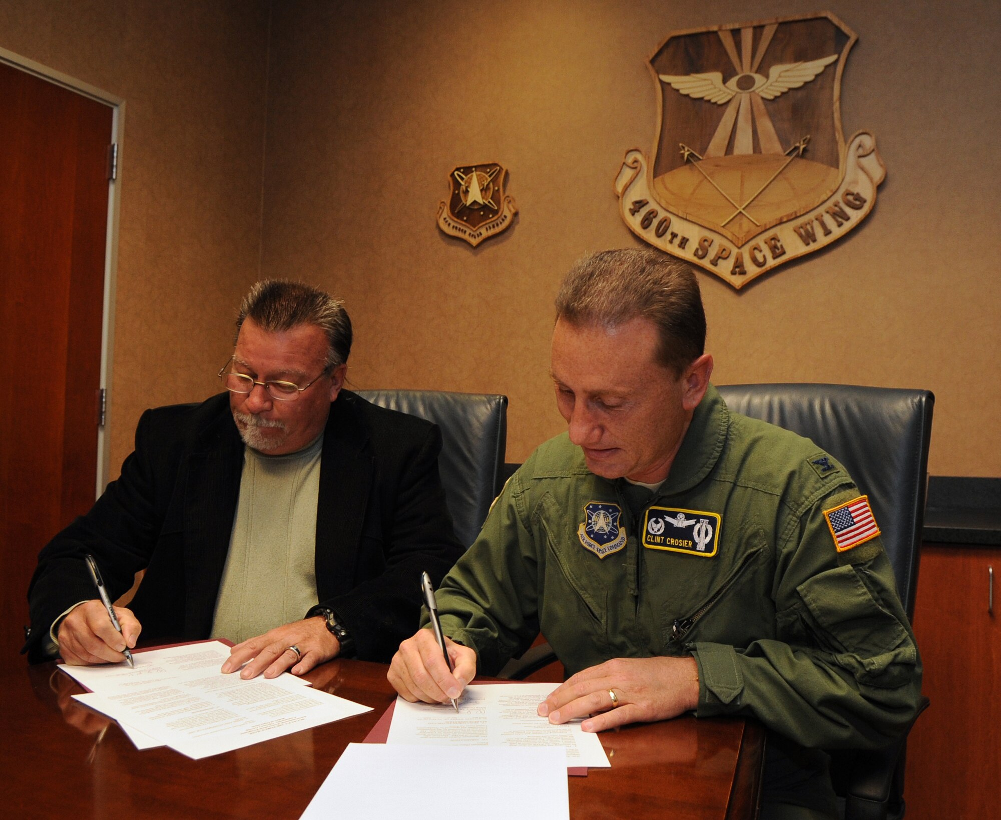 Buckley Air Force Base, Colo. -- Russell Clayshulte and Col. Clint Crosier, 460th Space Wing commander, sign the Buckley Air Force Base Community Advisory Group charter, Oct. 13.  The CAG is made up of base, community members, local, state and federal regulators who work toward environmental cleanup of the base. Mr. Clayshulte has been the CAG co-chair with five previous installation commanders at Buckley. (U.S. Air Force photo by Senior Airman John Easterling)