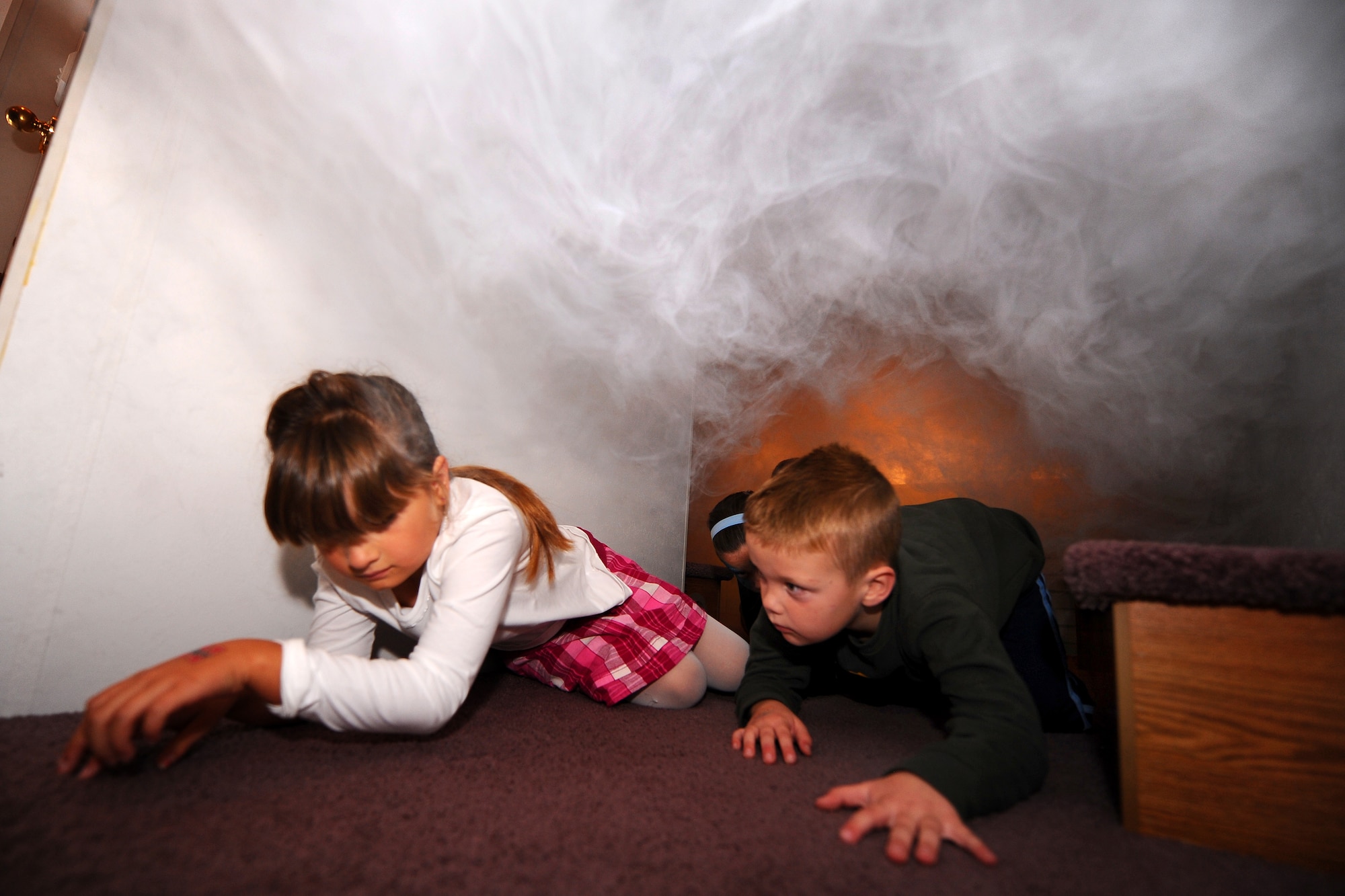 OFFUTT AIR FORCE BASE, Neb. - Eight-year-old Kylie Yolovich and five-year-old Simon Kallemya crawl through a miniature house designed to simulate a fire in the home, giving them safe and realistic training on how to escape a house fire as part of the Offutt Firehouse's Open House held Oct. 10.  National Fire Prevention Week starts on the first Sunday in October and ends the following Saturday, which is also Fire Service Recognition Day.  U.S. Air Force Photo by Josh Plueger