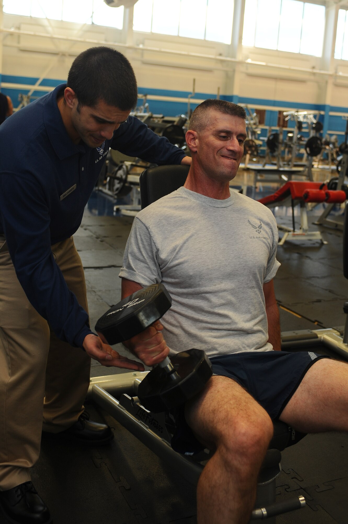 Senior Airman Zachary Christy (left), 28th Force Support Squadron fitness specialist, assists an Airman with a bicep curl at Bellamy Fitness Center here, September 22. The fitness center has a variety of workout equipment and programs designed to keep Airmen fit. (U.S. Air Force photo/Senior Airman Kasey Zickmund)