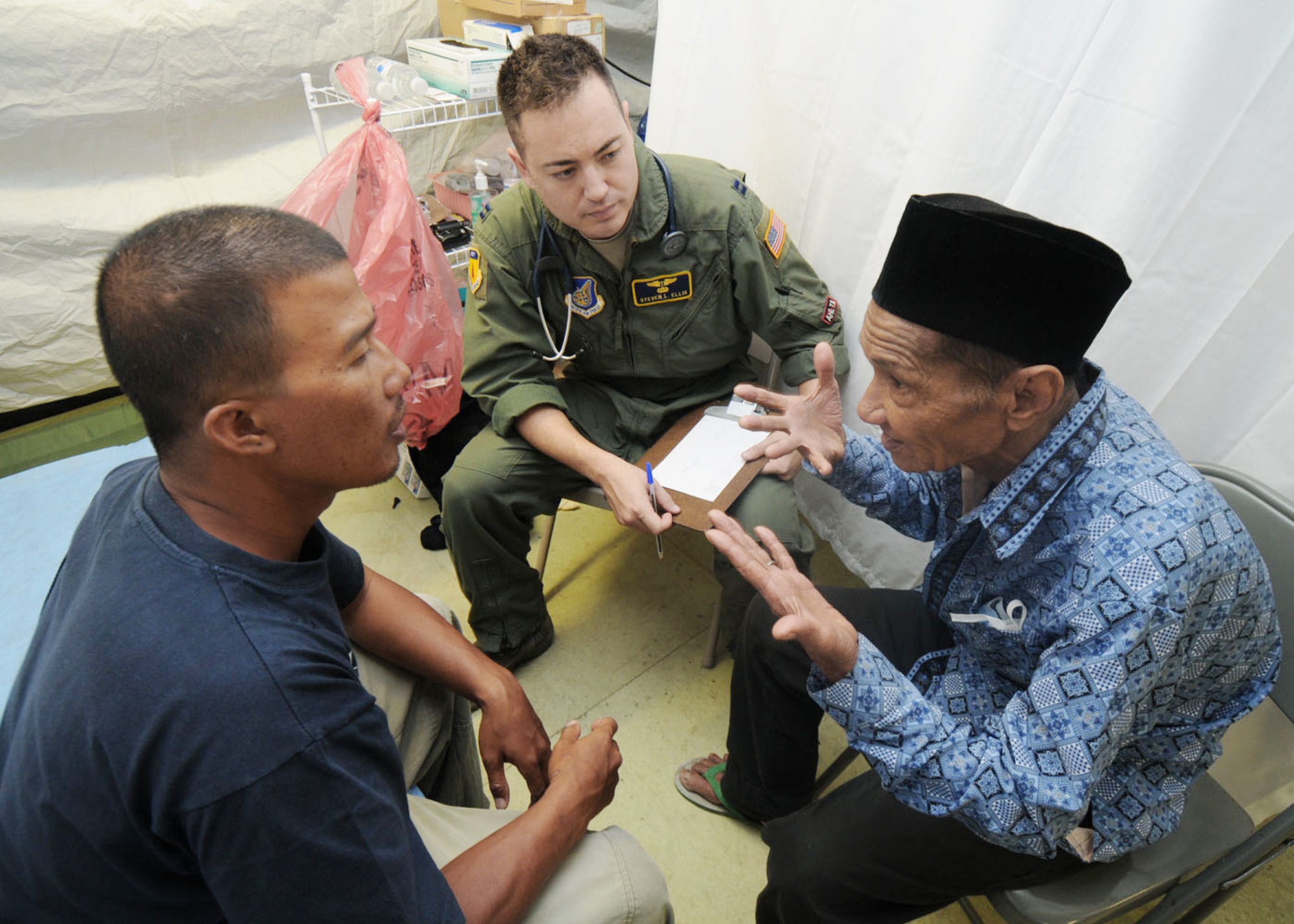 Capt. Steven Ellis collects medical history information from a patient with the help of Khairul, a local interpreter, Oct. 10, 2009, in Padang, Indonesia. Captain Ellis is a flight surgeon from the 36th Medical Group at Andersen Air Force Base, Guam, and is deployed here with an Air Force humanitarian assistance rapid response team to provide medical assistance to those affected by the recent earthquakes. (U.S. Air Force photo/Staff Sgt. Veronica Pierce) 
