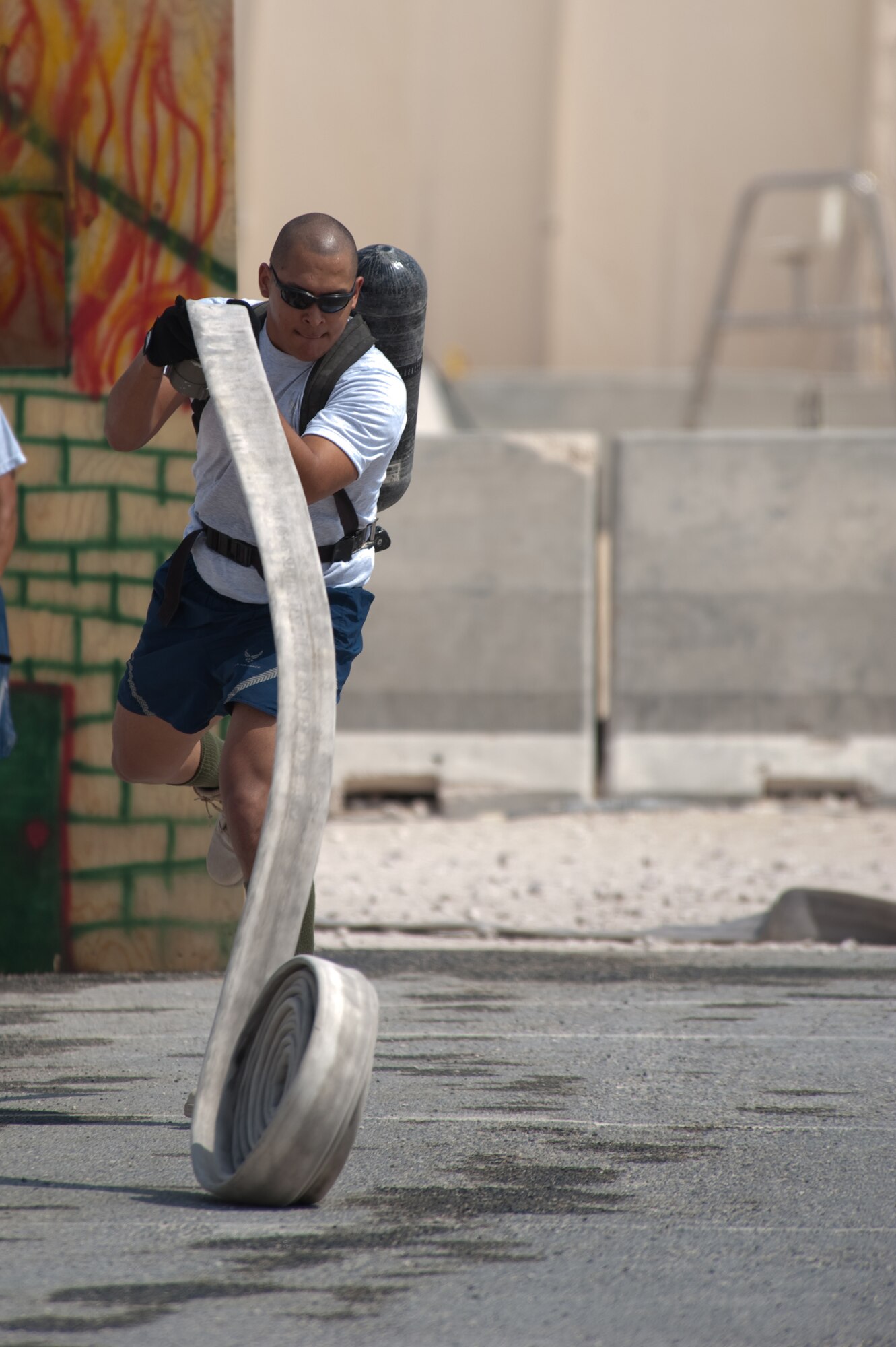 Airman 1st Class Zach Herrera, 379th Expeditionary Civil Engineer squadron, competes in the hose throw event during a fire muster competition, Oct. 11, 2009, in Southwest Asia. The 379th Civil Engineer squadron Fire Department concluded fire safety week here with a muster that simulated multiple events and exercises firefighters perform on a regular basis. (U.S. Air Force photo/Staff Sgt. Robert Barney)