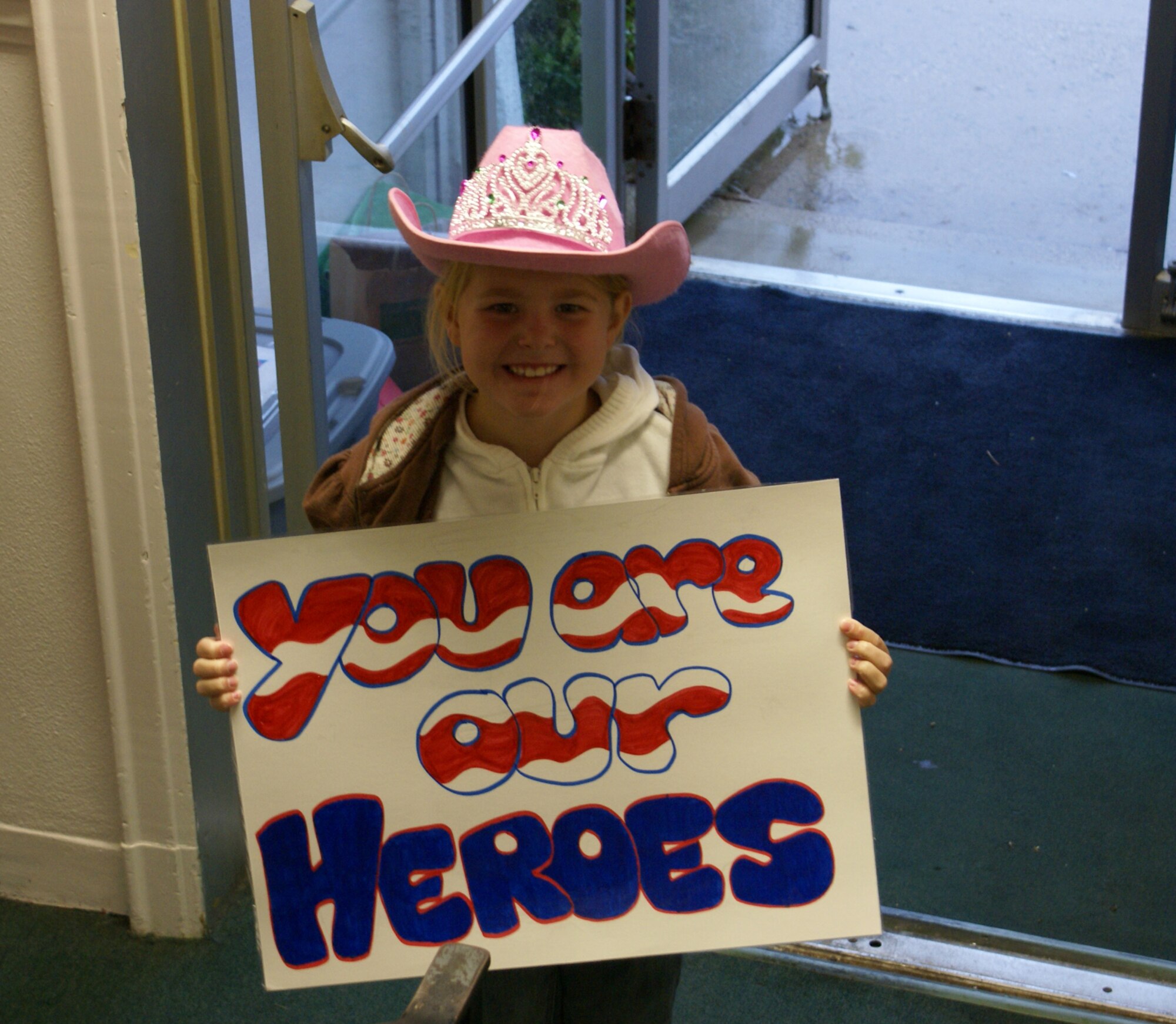 WRIGHT-PATTERSON AIR FORCE BASE, Ohio – McKenzie Neri, daughter of Staff Sgt. Mike Neri, 445th Airlift Wing, holds a sign for 35 World War II and Korean veterans and their families as they boarded a bus in front of the American Legion Post in Piqua, Ohio, for a weekend trip to Washington, D.C., Oct. 2.  The group received a special sendoff from active duty, reserve and civilians stationed at Wright-Patterson Air Force Base, as well as local school children, community leaders and government employees. (Courtesy photo)