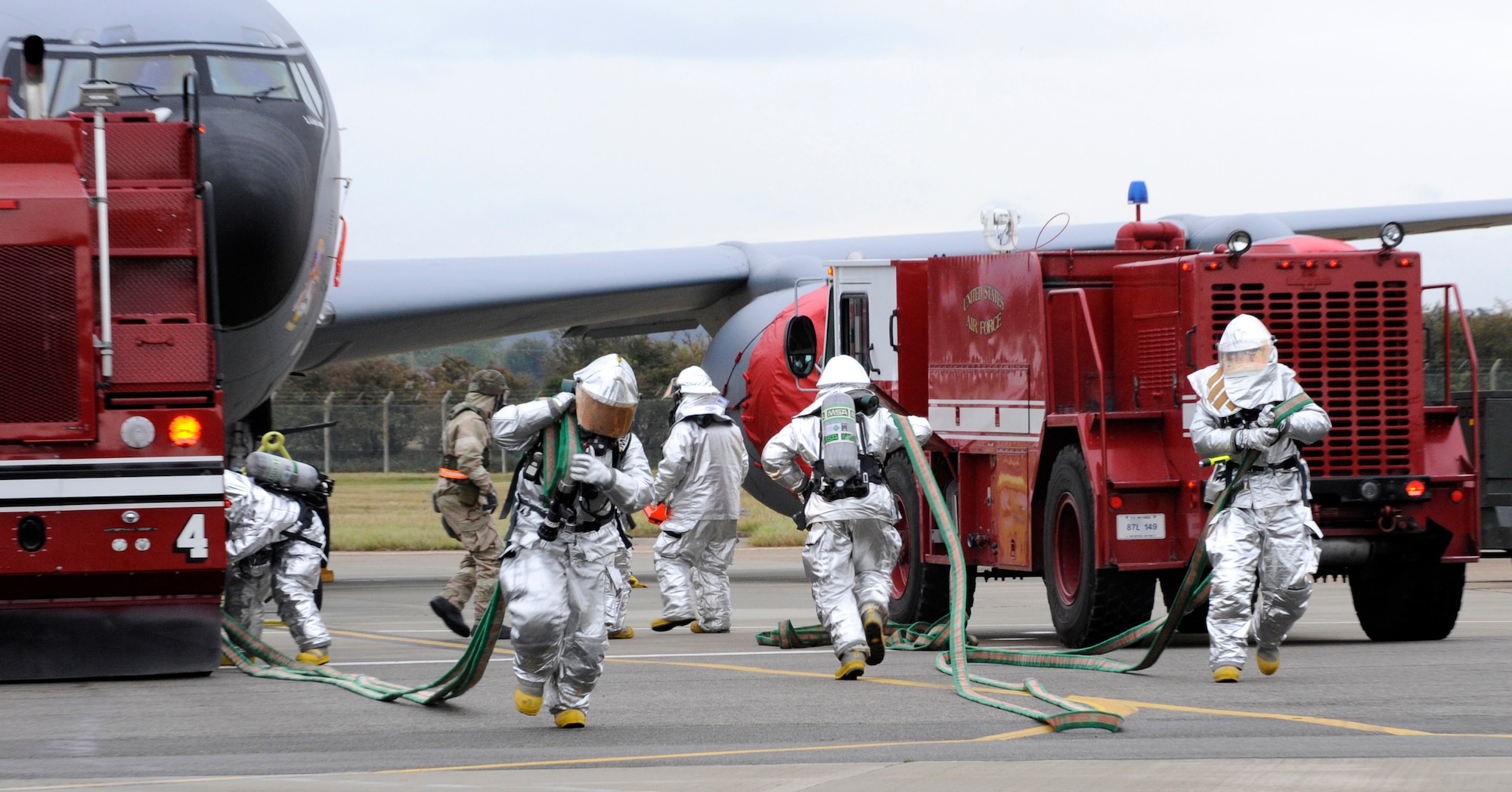 RAF MILDENHALL, England -- Base firefighters unravel their hoses as they demonstrate their ability to extract aircrew from a simulated burning KC-135 Stratotanker during the Operational Readiness Inspection Oct. 12.  The inspection tests aspects of pre-deployment and the base’s ability to operate in a deployed environment.  (U.S. Air Force photo/Staff Sgt. Christopher L. Ingersoll)
