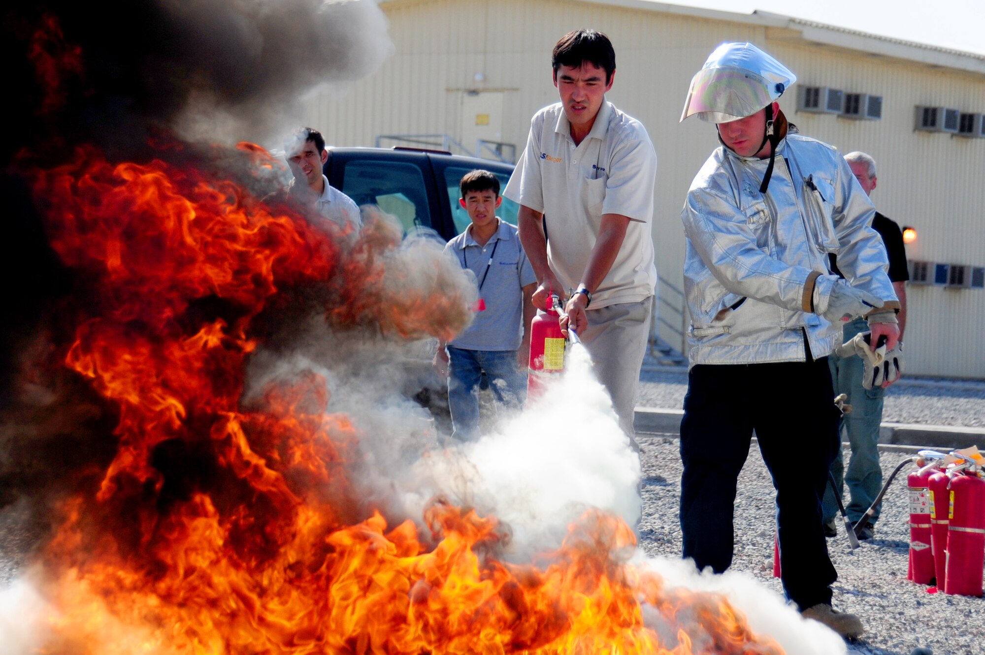 TRANSIT CENTER AT MANAS, Kyrgyzstan -- Fire Truck Operator Josh Detzel, 376th Expeditionary Civil Engineer Squadron, instructs fire extinguisher training to civilian contractors at the Transit Center, Oct. 7, 2009. Over 150 students attended the class, throughout Fire Prevention Week, being taught pull, aim, squeeze, and sweep or 'PASS' techniques. (U.S. Air Force photo/Senior Airman Steele C. G. Britton)