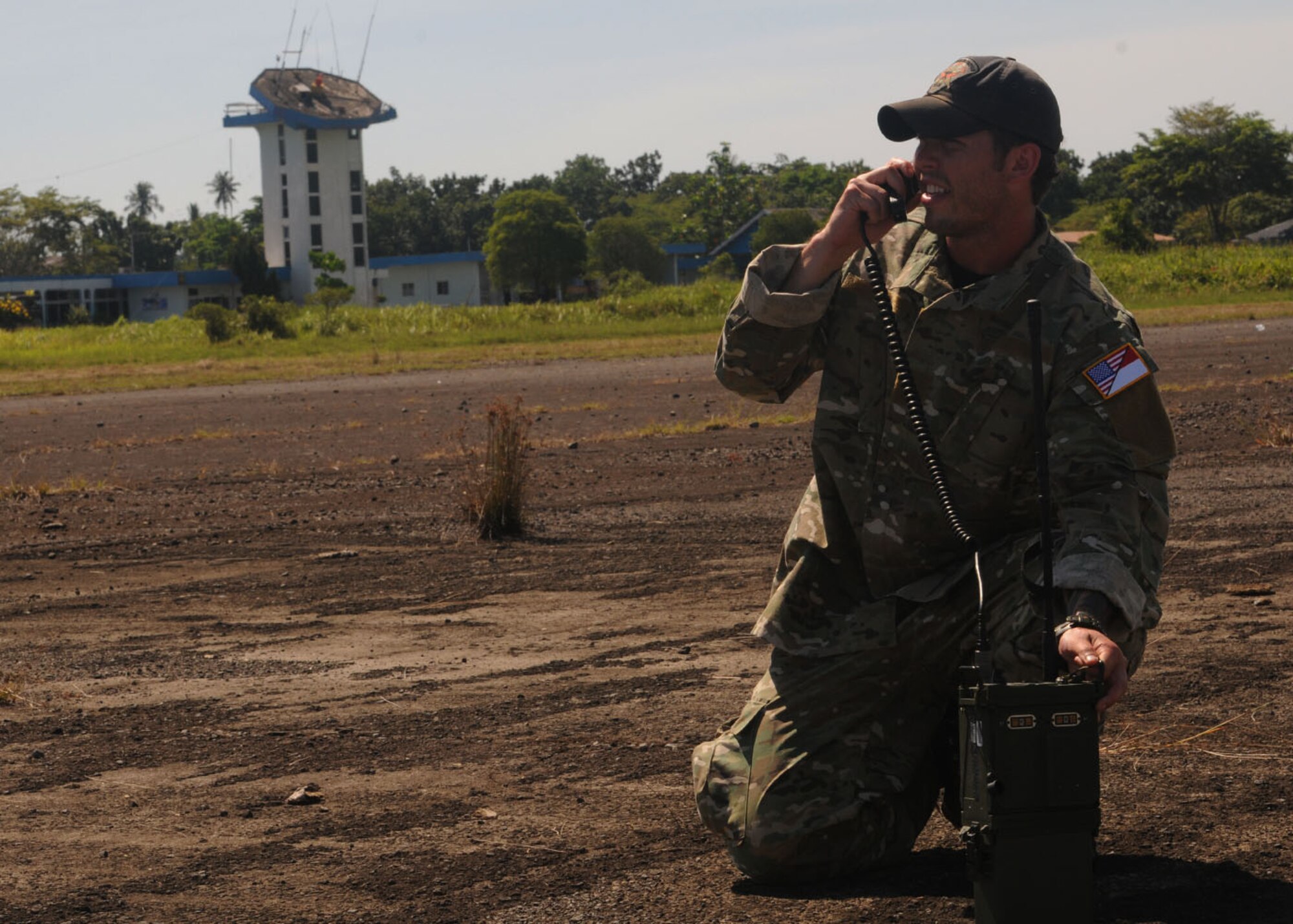 PADANG, Indonesia --  A U.S. Air Force combat controller from the 320th Special Tactics Squadron at Kadena Air Base, Japan, relays air traffic control information to incoming U.S. aircraft landing at Tangbing Airfield here Oct. 9. The ATC tower (background) was severely damaged in the Sept. 30 earthquake which struck here, effectively stopping the flow of aircraft. Combat controllers and U.S. Marines continue to provide ATC capabilities to allow U.S., Australian and Indonesian aircraft to transfer humanitarian supplies into the region. (U.S. Air Force photo/Staff Sgt. Veronica Pierce)