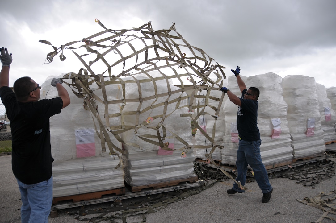 Tony Quinata, right, and Monte Garrido, both from DZSP 21, throw cargo netting over a pallet of FEMA tents Oct. 9 at Andersen Air Force Base, Guam, for delivery to American Samoa after the area was struck by an earthquake and resulting tsunami. A total of 13 pallets containing 800 tents will be flown by an Air Force C-17 Globemaster III in support of FEMA's humanitarian aid mission. (U.S. Air Force photo by Master Sgt. Carrie Hinson) 