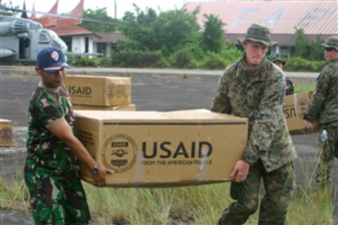 U.S. Marine Corps Lance Cpl. Matthew Stiltner (right) a landing support specialist from Combat Logistics Battalion 31, 31st Marine Expeditionary Unit and an Indonesian service member carry a box of supplies to a load point during a humanitarian assistance and disaster relief effort in Padang, Indonesia, on Oct. 12, 2009.  The supplies will be delivered as part of the U.S. military response to a request for assistance by the Indonesian government after a 7.6 magnitude earthquake struck the country on Sept. 30, 2009.  