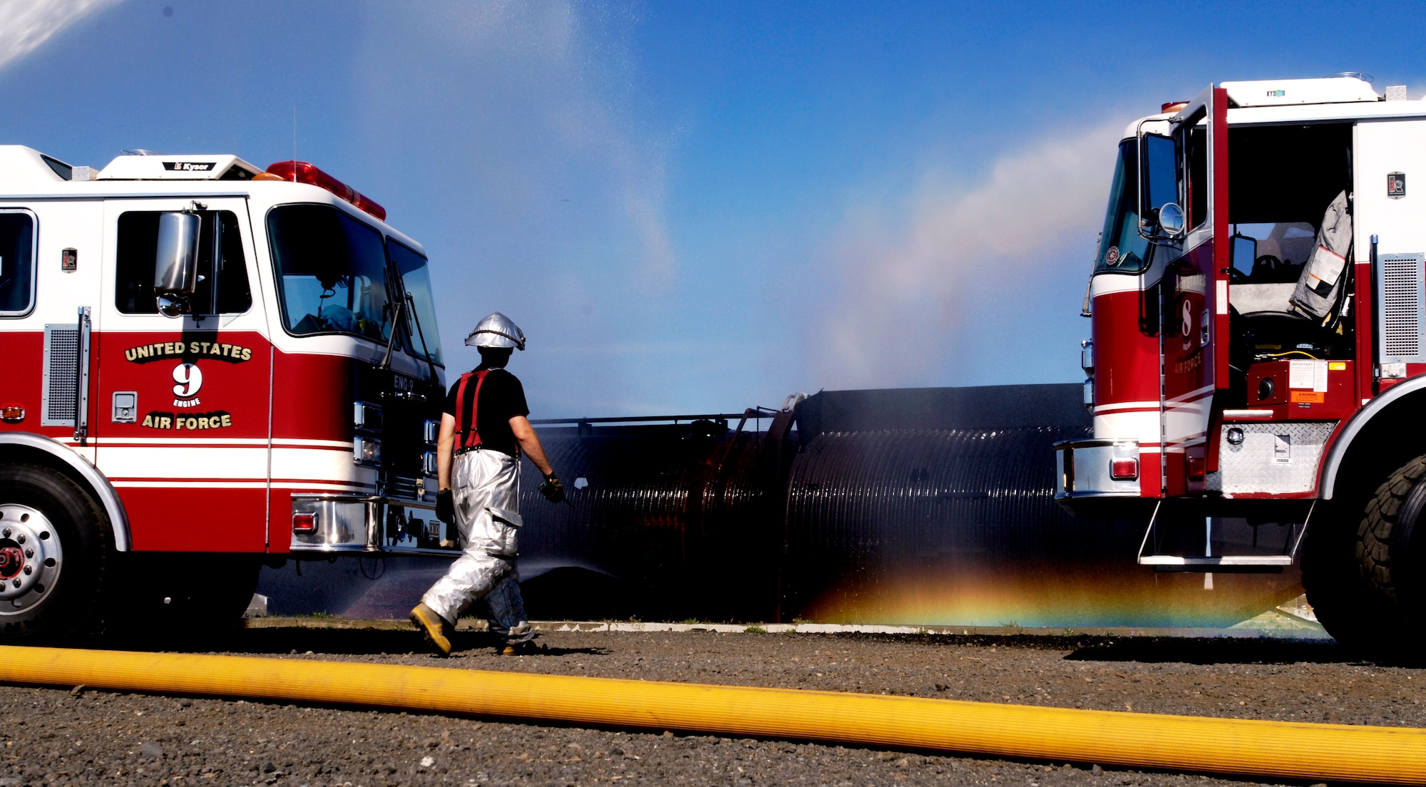 A rainbow forms between two fire rescue vehicles here as the 92nd Civil Engineering Squadron fire fighters hose down a mock aircraft set on fire for training purposes Sept. 10. (U.S. Air Force photo/ Airman 1st Class Natasha E. Stannard)