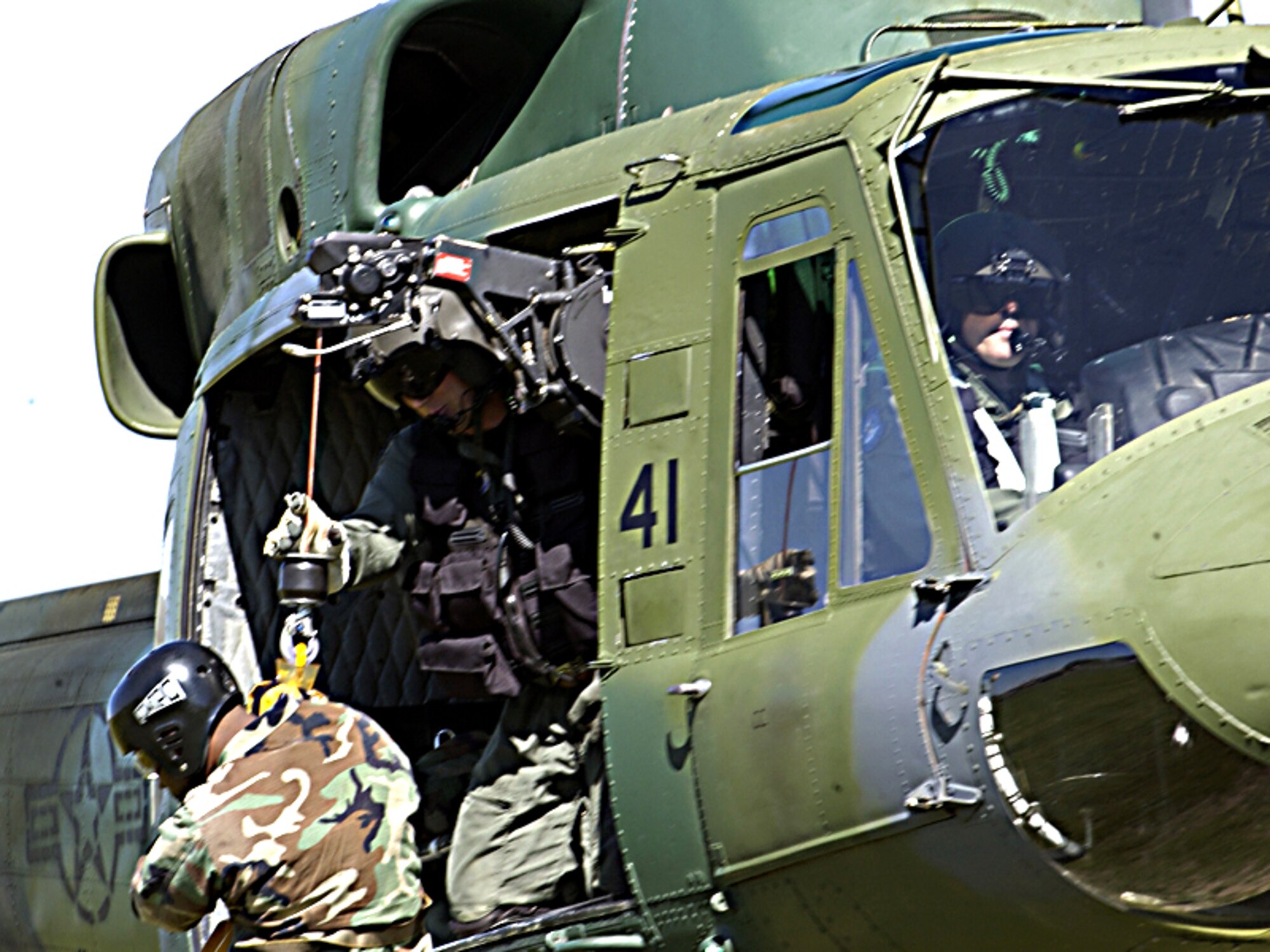 A flight engineer with the 36th Rescue Flight  here helps lower a medic to the ground from a U-H1N Huey helicopter. (US Air Force courtesy photo)