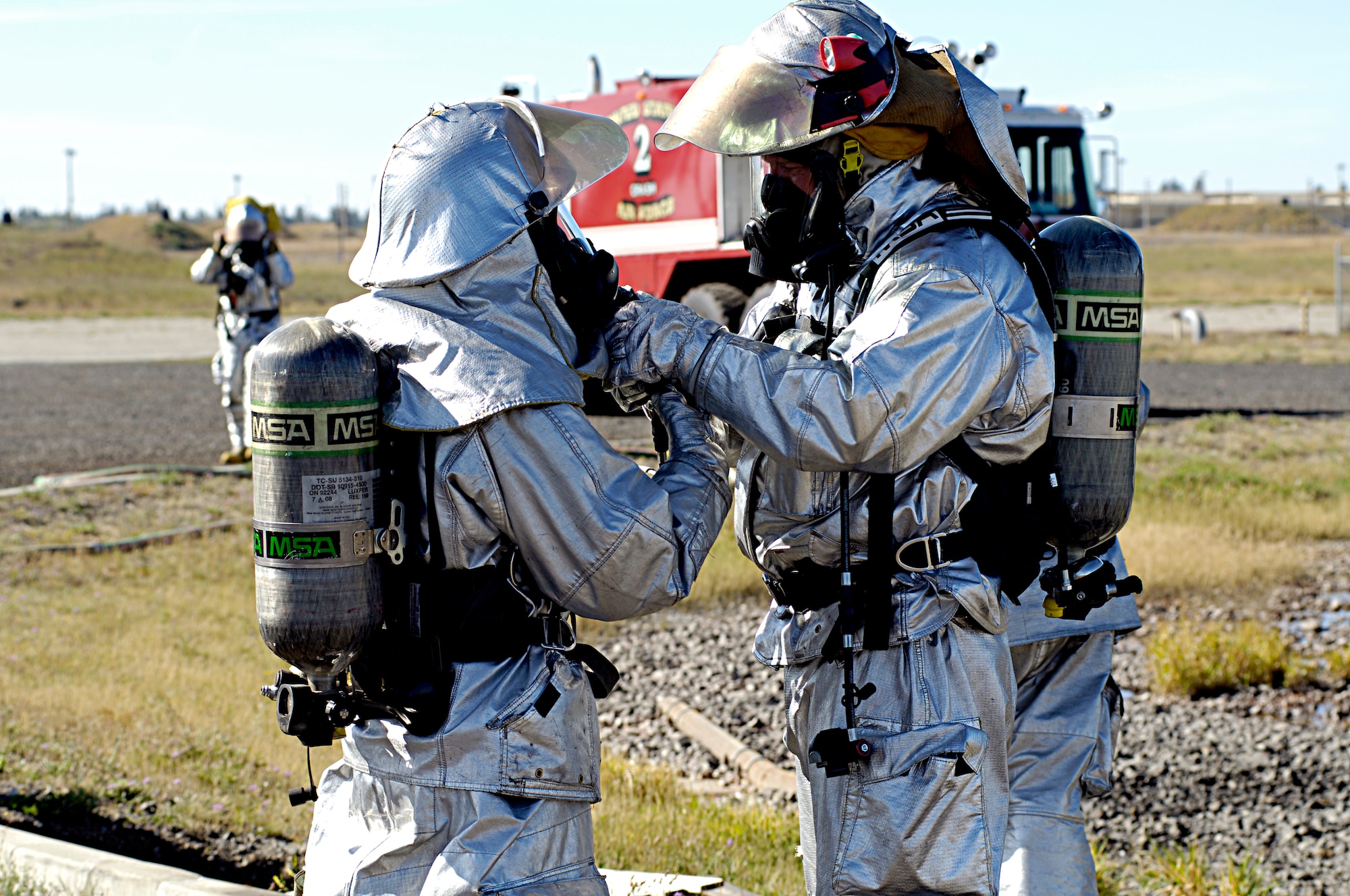 Staff Sgt. Ty Miller, 92nd Civil Engineering Squadron fire fighter, checks Senior Airman David Adriatico’s, 92nd Civil Engineering Squadron fire fighter, mask before entering and fighting the fire set in a mock aircraft for training purposes here Sept. 10. (U.S. Air Force photo/ Airman 1st Class Natasha E. Stannard)