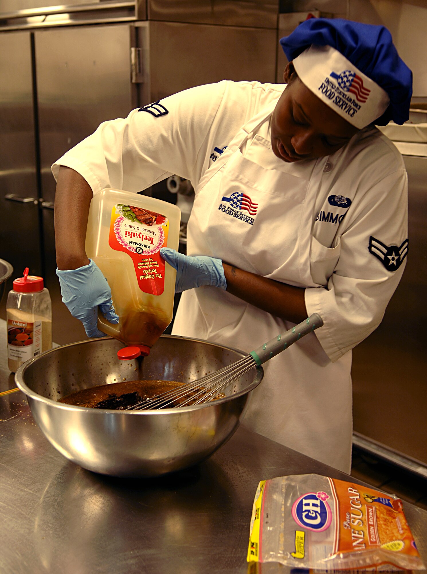 Airman 1st Class Sarafina Simmons, 92nd Force Support Squadron services chef, seasons teriyaki chicken for dinner at the Warrior dining facility here Sept. 22. Airman Simmons works the afternoon shift at the dining facility in which she serves lunch, and prepares and serves dinner. (U.S. Air Force photo/Airman 1st Class Natasha E. Stannard)