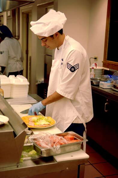 Senior Airman Mathew Baumann, 92nd Force Support Squadron services chef, prepares a deli wrap for a patron in the grill line at the Warrior dining facility here Sept. 22. Airman Baumann works the afternoon shift at the dining facility in which he serves lunch, and prepares and serves dinner. (U.S. Air Force photo/Airman 1st Class Natasha E. Stannard)