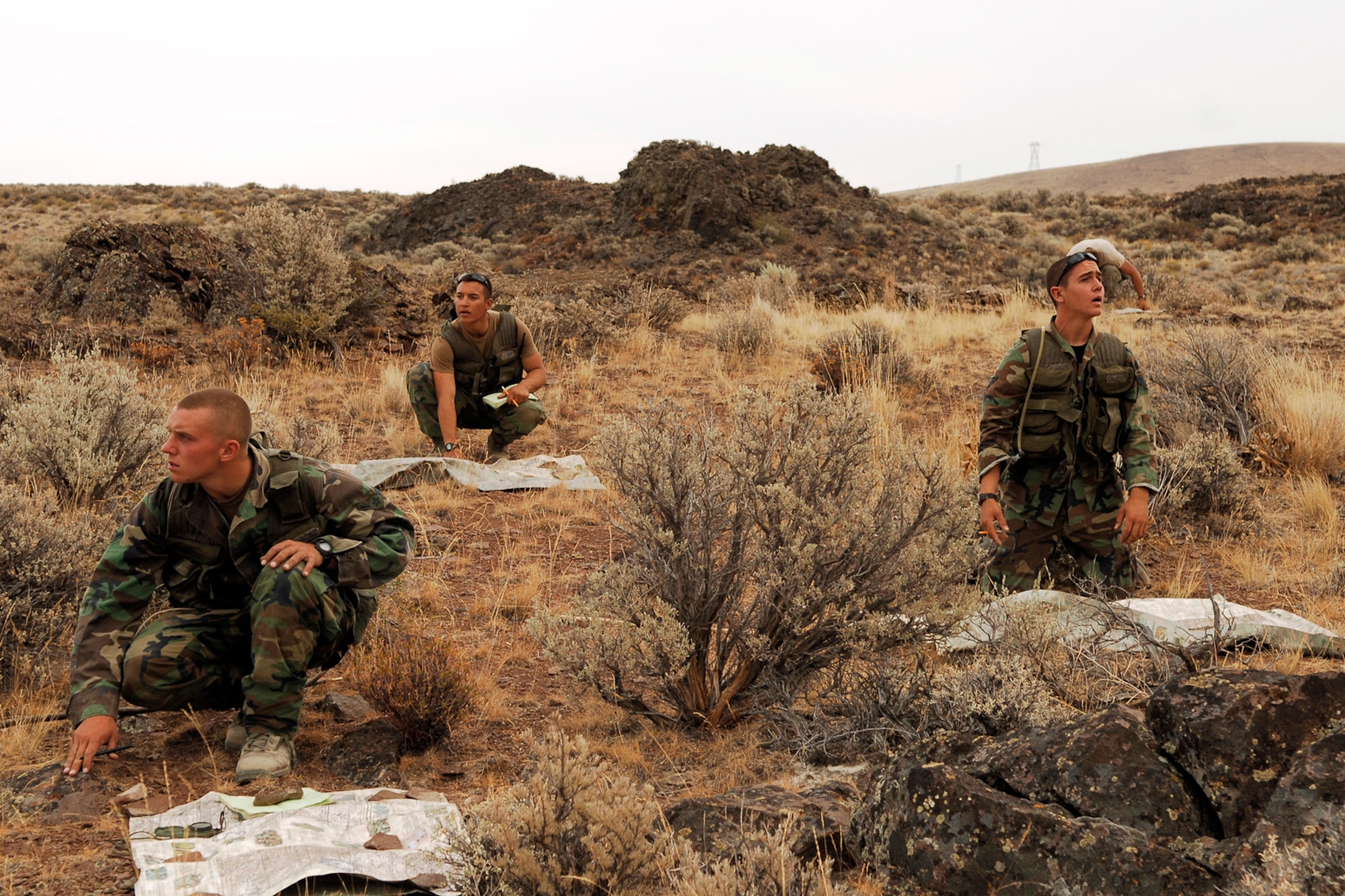 Three Survival, Evasion, Resistance and Escape technical school students intensely peer above their maps as they attempt to locate their position in the George, Wash., area around the Columbia River. (U.S. Air Force photo / Senior Airman Joshua K. Chapman)
