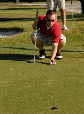 Airman 1st Class David Carlson places his golf ball on the green before putting during the 437th Airlift Wing Golf Tournament at Wrenwoods Golf Course here Oct. 9. Airman Carlson's putt put his team at three under par after five holes played. Airman Carlson is a crew chief with the 437th Maintenance Squadron. (U.S. Air Force photo/Staff Sgt. Daniel Bowles)