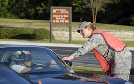 Senior Airman Meagan Bustillo greets a motorist at the Dorchester Road main gate during a Safety Sendoff event before the start of the holiday weekend Oct. 9. Airman Bustillo handed out magnets with important contact information for base support agencies to people exiting the base during the full two hours of the event from 3 to 5 p.m. Airman Bustillo is a safety apprentice with the 437th Airlift Wing Safety Office. (U.S. Air Force photo/Staff Sgt. Daniel Bowles)