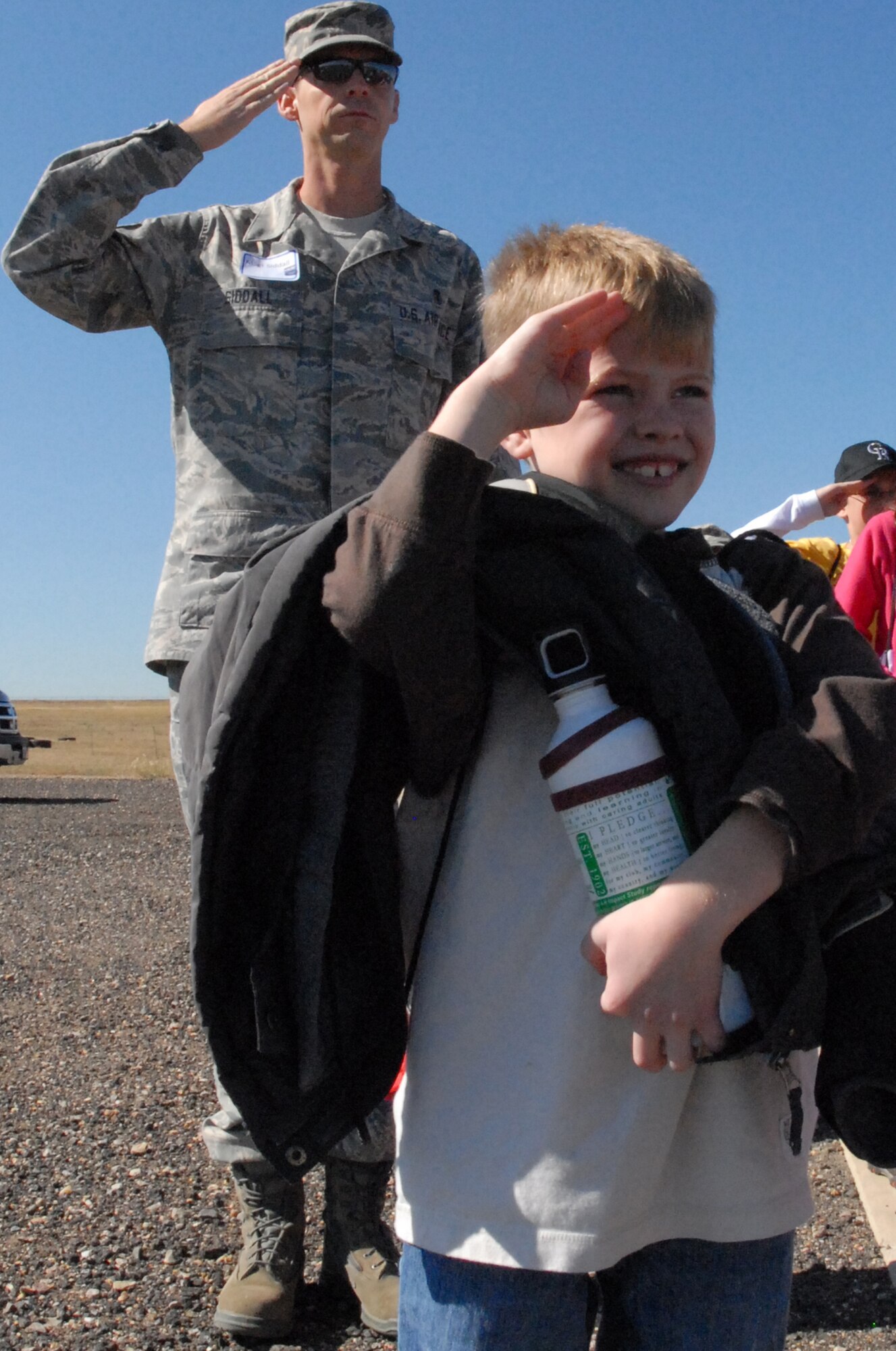 Master Sgt. Joseph Siddall, 460th Medical Operations Squadron, a volunteer troop commander and Buckley Youth salute during reveille, Oct. 3 at Buckley. The day became still for the only quiet moment of the day, as all the children paid respect to the flag during a Mile High Honor Guard demonstration. (U.S. Air Force photo by Tech. Sgt. J. LaVoie)