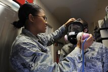MINOT AIR FORCE BASE, N.D. -- Airman 1st Class Anjeolika Rodriguez, ensures a good seal on her coworker, Senior Airman Raven Motz, both 5th Medical Operations Squadron bioenvironmental engineer flight technicians, while training on a gas mask fit test here, Oct. 14.  Bioenvironmental engineers conduct respirator and gas mask fit tests in order to protect and maintain a healthy work force.  They also perform environmental, occupational and radiological surveillance, and serve as mission enhancers during emergency management response operations. (U.S. Air Force photo by Tech. Sgt. Lee A. Osberry Jr.)