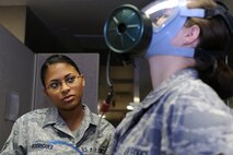 MINOT AIR FORCE BASE, N.D. -- Airman 1st Class Anjeolika Rodriguez, ensures a good seal on her coworker, Senior Airman Raven Motz, both 5th Medical Operations Squadron bioenvironmental engineer flight technicians, while training on a gas mask fit test here, Oct. 14.  Bioenvironmental engineers conduct respirator and gas mask fit tests in order to protect and maintain a healthy work force.  They also perform environmental, occupational and radiological surveillance, and serve as mission enhancers during emergency management response operations. (U.S. Air Force photo by Tech. Sgt. Lee A. Osberry Jr.)
