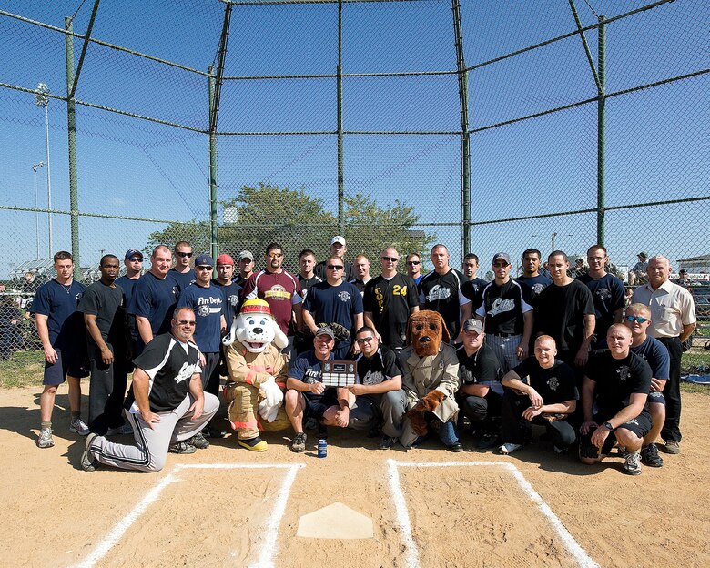 The 436th Security Forces Squadron and fire department softball teams pose for a photo before the start of the 'Battle of the Badges' game Oct. 9. The 436th SFS defeated the fire department 19-7.  The 'Battle of the Badges' is an annual game in which 436th SFS competes against 436th CES in a friendly game of softball to see whether the police or firefighters will be victorious. (U.S. Air Force photo/Jason Minto)