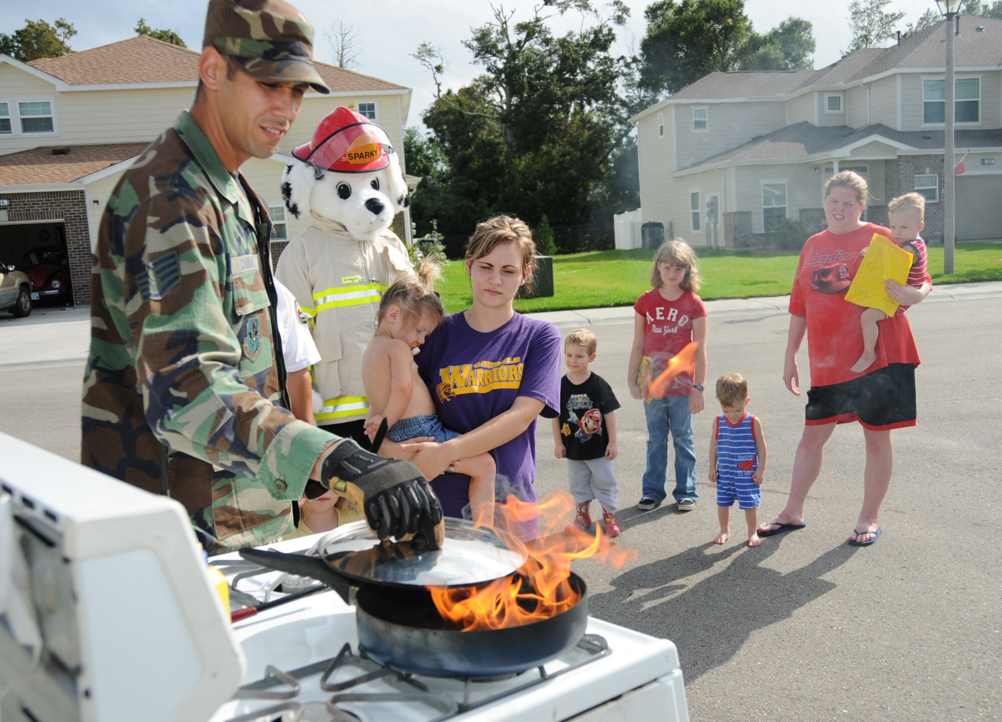 Staff Sgt. Stephen Crandall from the fire department demonstrates how to extinguish a grease fire to residents of Thrower Park Oct. 6.  (U.S. Air Force photo by Kemberly Groue)