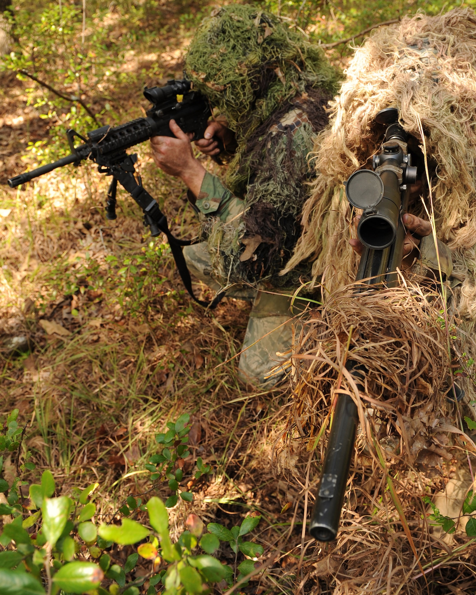 Senior Airman Dane Coppini (left) and Staff Sgt. Carl Hook, 19th Security Forces Squadron sharp shooters, sneak through the forest in their ghillie suits to blend into the environment Oct. 8 during training at Camp Robinson.  Airman Coppini and Sergeant Hook recently received training in the Close Precision Engagement Course on Camp Robinson and are now training for the Inter-Service Sniper Sustainment Training Exercise held at Fort Chaffee, Ark. (U.S. Air Force photo by Staff Sgt. Chad Chisholm)