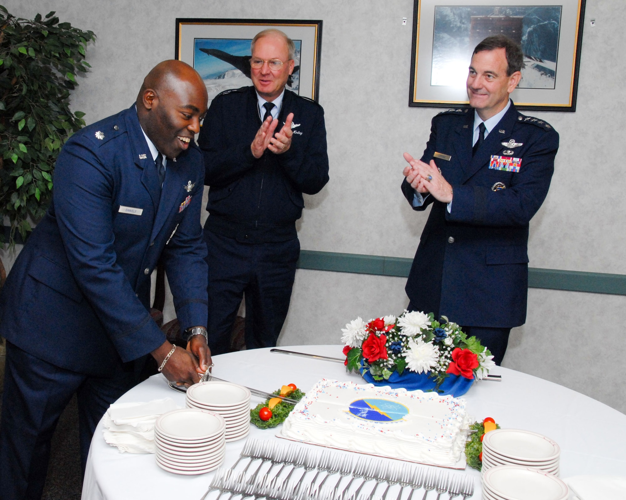 (From right) Gen. Stephen Lorenz, Air Education and Training Command commander, and Gen. Craig McKinley, chief of National Guard Bureau, applaud Lt. Col. Ronald Daniels, the new Detachment 12, Air National Guard Readiness Center commander as he cuts a cake during the activation ceremony Oct. 2. (U.S. Air Force photo/Bud Hancock)