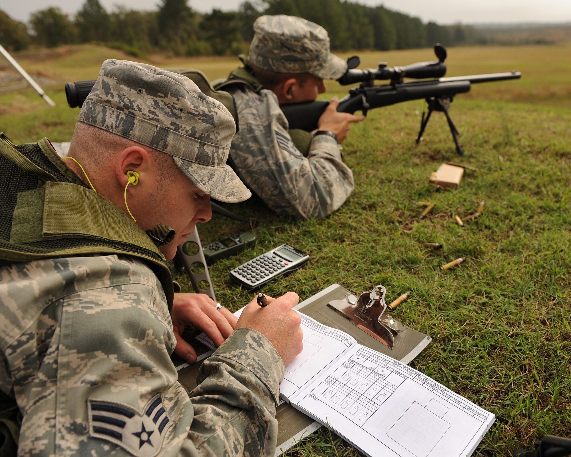 Senior Airman Dane Coppini, 19th Security Forces Squadron sharp shooter, logs the previous shot taken by Staff Sgt. Carl Hook, 19 SFS sharp shooter, into a log book Oct. 8 during training held at Camp Robinson.  Airman Coppini uses the log book to track shot location, distance, wind conditions, humidity, temperature, altitude and other information to calculate future shots taken under the same conditions.  Airman Coppini and Sergeant Hook recently received training in the Close Precision Engagement course at Camp Robinson (U.S. Air Force photo by Staff Sgt. Chad Chisholm)