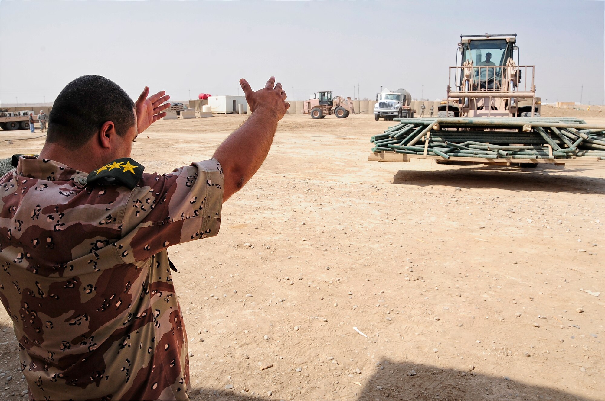 ALI BASE, Iraq - Iraqi Army Capt. Ali with the 10th Iraqi Army Division ground guides a U.S. Air Force member of the 407th Expeditionary Civil Engineer Squadron at Camp Mittica, Iraq, Oct. 14, 2009. The squadron made significant donation of equipment and building material to the 10th Iraqi Army Division assigned to Camp Mittica. (U.S. Air Force photo/Senior Airman Tony R. Ritter)