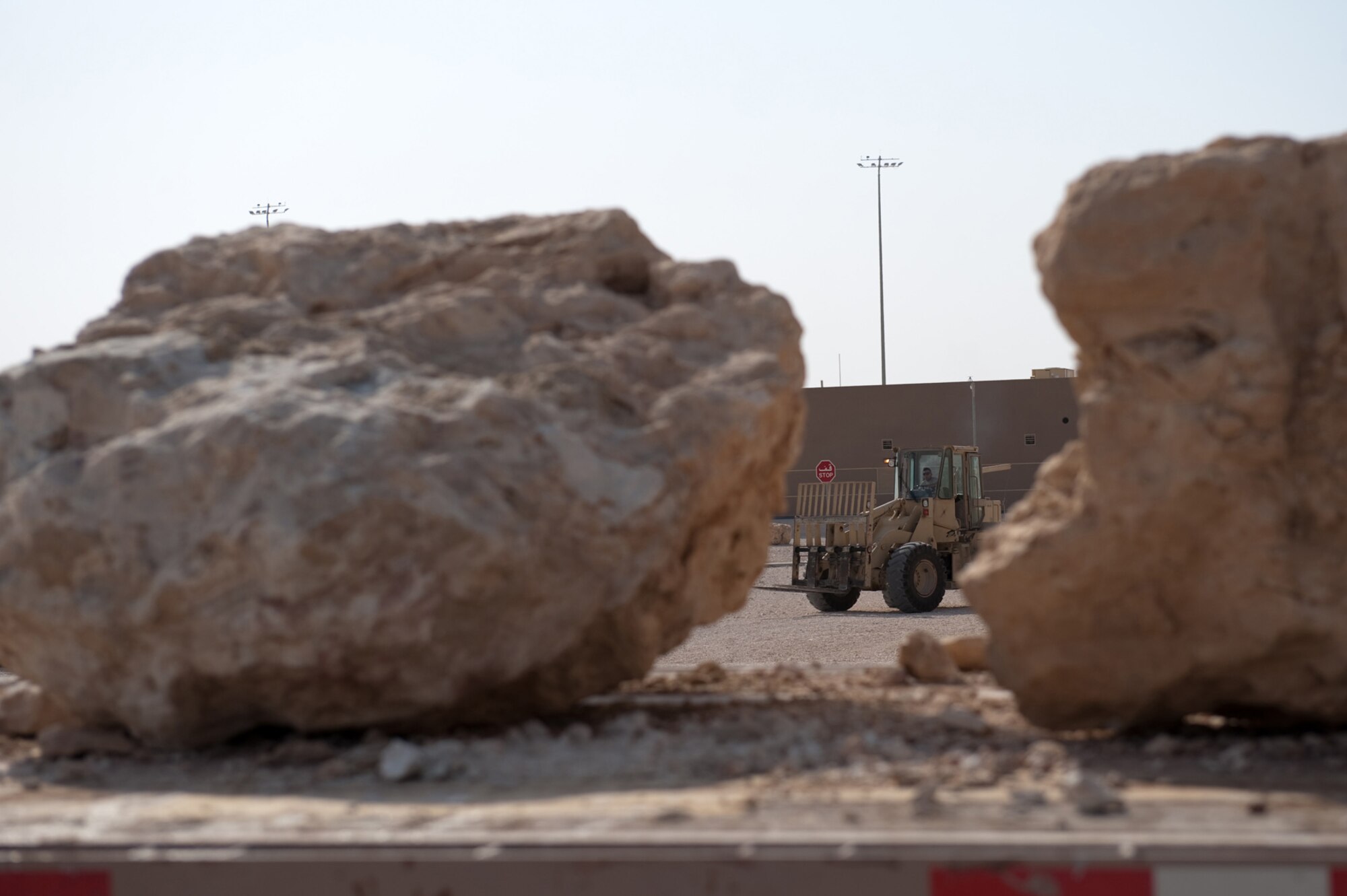 Senior Airman Walter Herandez, 379th Expeditionary Civil Engineer squadron pavement and heavy equipment journeyman, places a boulder, Oct. 11, 2009, in Southwest Asia. The 379 ECES pavement and heavy equipment section placed large boulders around U.S. Air Force assets for an added measure of force protection. (U.S. Air Force photo/Staff Sgt. Robert Barney) 